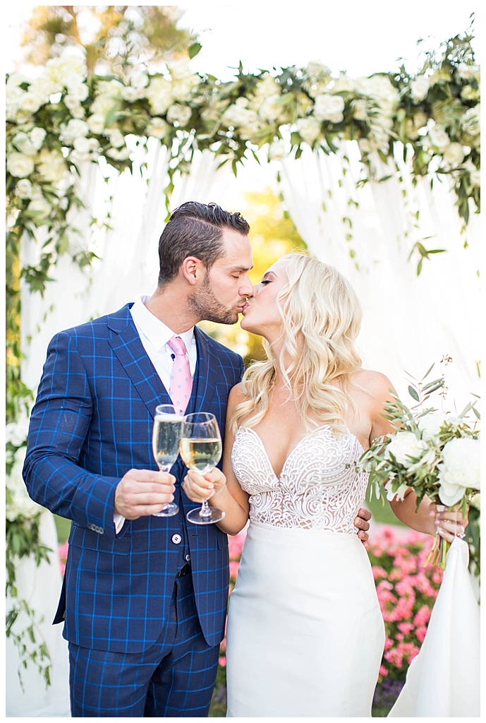 bride in two piece wedding dress and groom kissing in custom blue suit at Arizona Biltmore