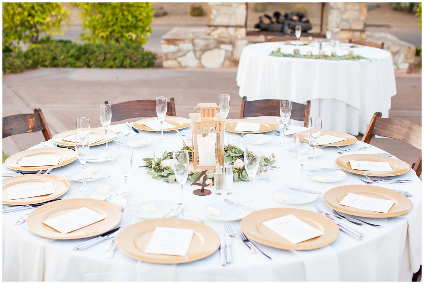 Elegant wedding table at reception with gold chargers and greenery