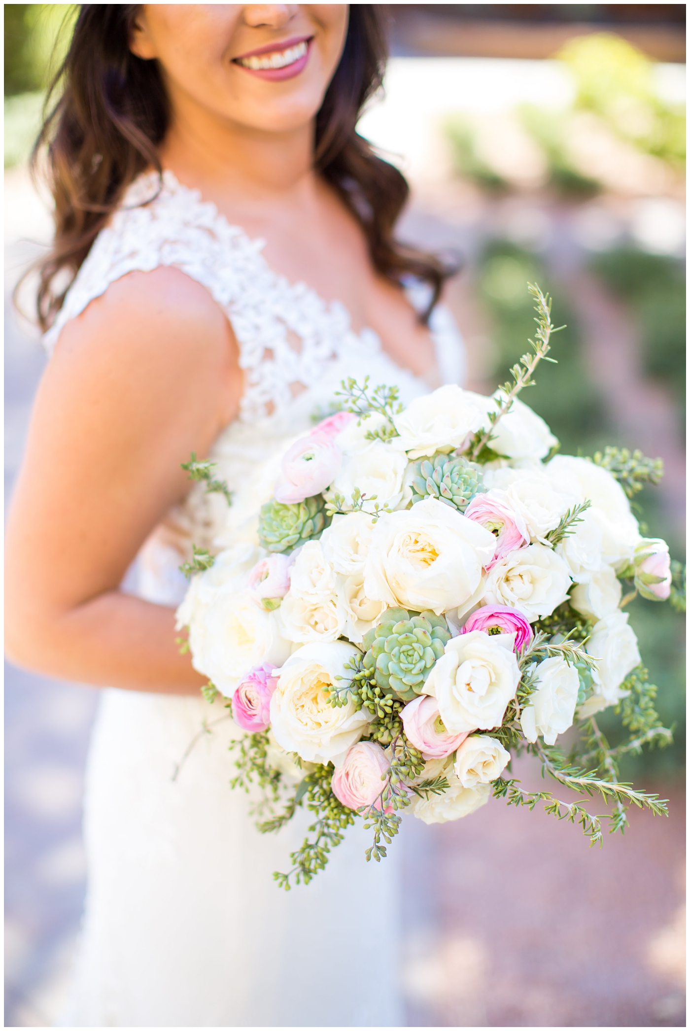 Gorgeous brunette bride in Justina Alexander wedding dress holding white rose, pink ranunculus, and green succulents bouquet
