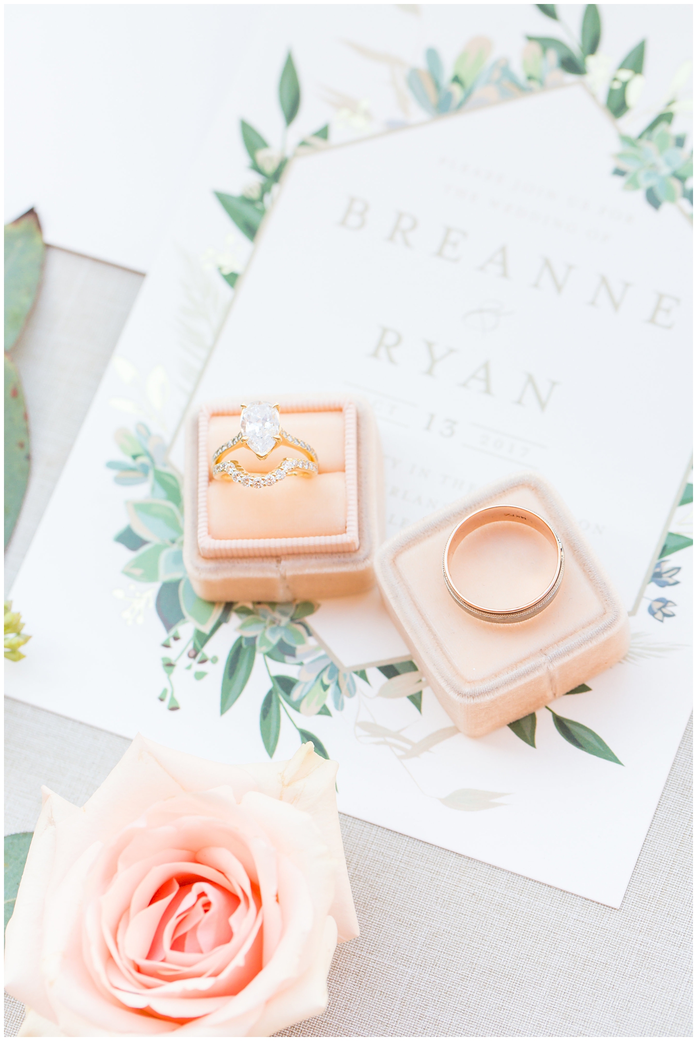 Wedding rings in pink mrs. box on top of elegant wedding invite with green succulents