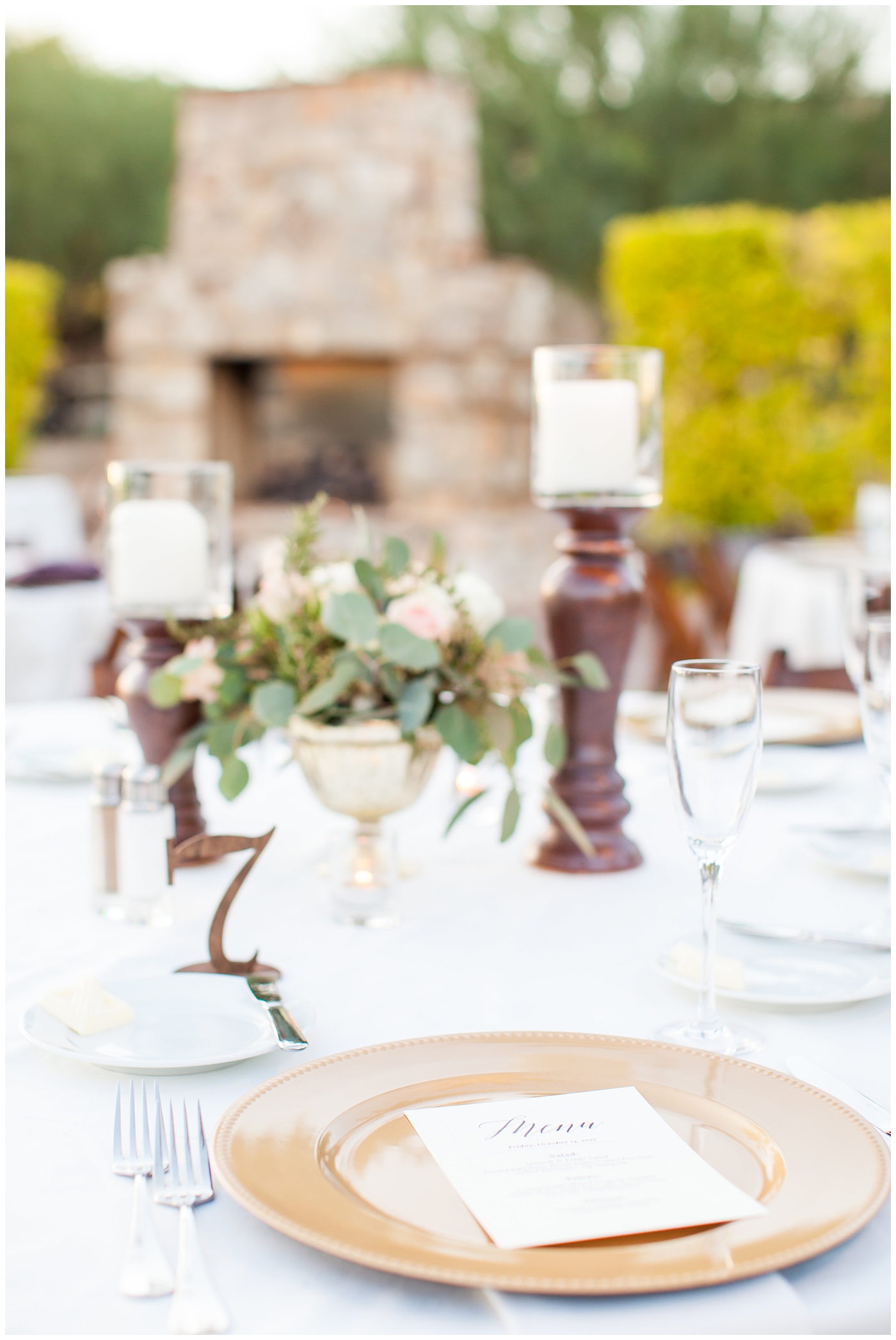 Elegant wedding table at reception with gold chargers and greenery