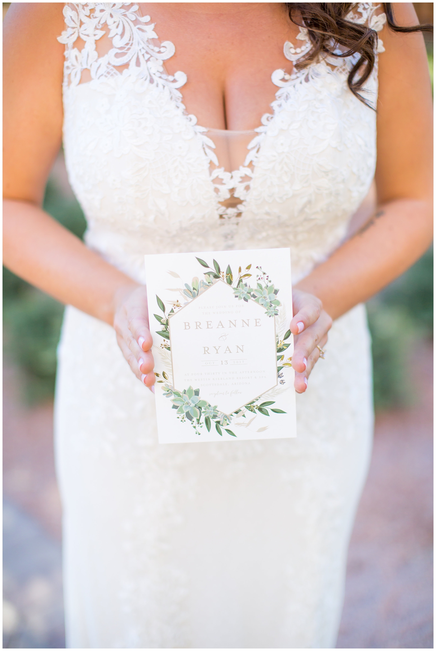 bride in Justina Alexander wedding dress holding elegant minted invitation with succulents