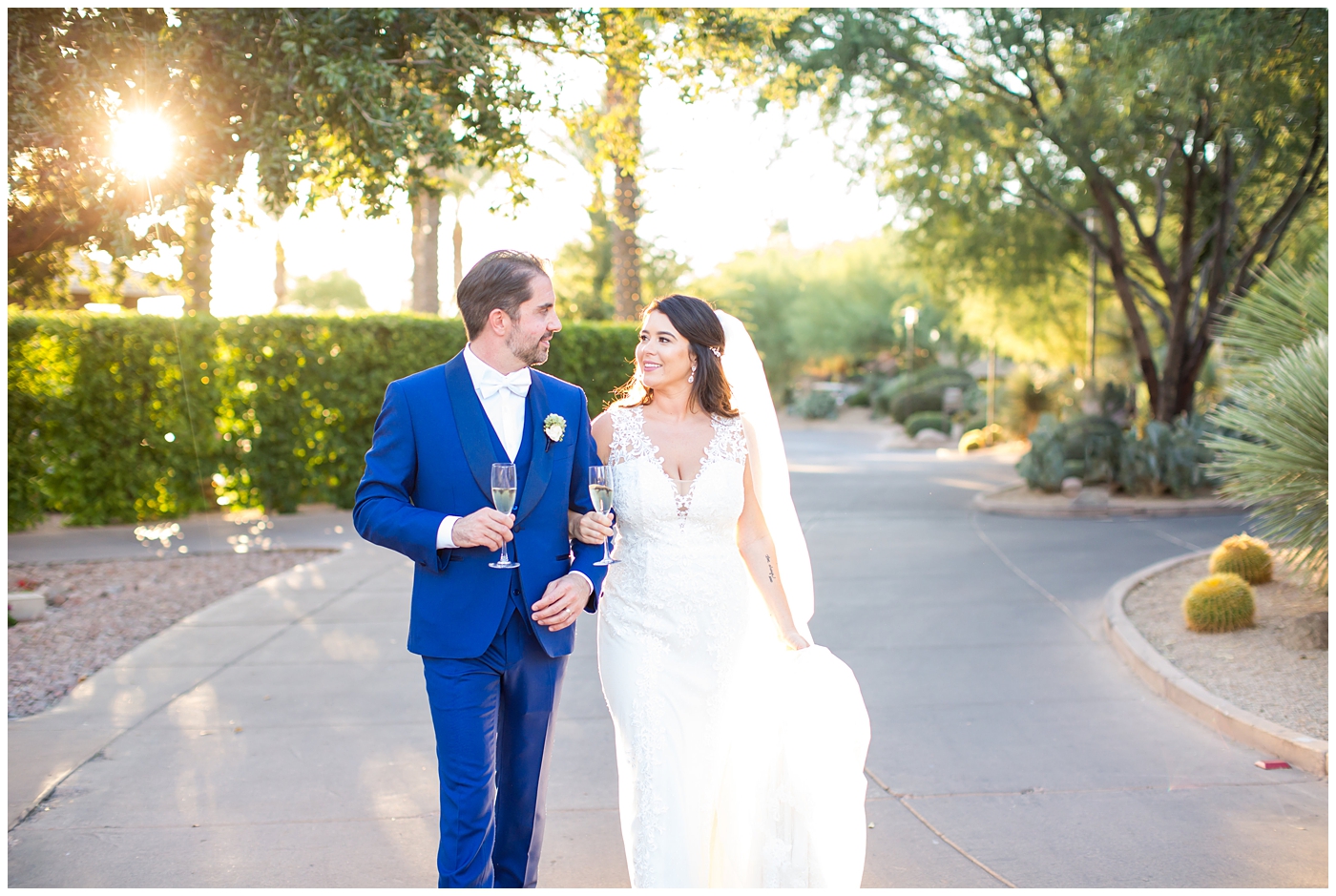 Bride in Justina Alexander dress with groom in custom Brother's Tailors blue suit walking with linked arms