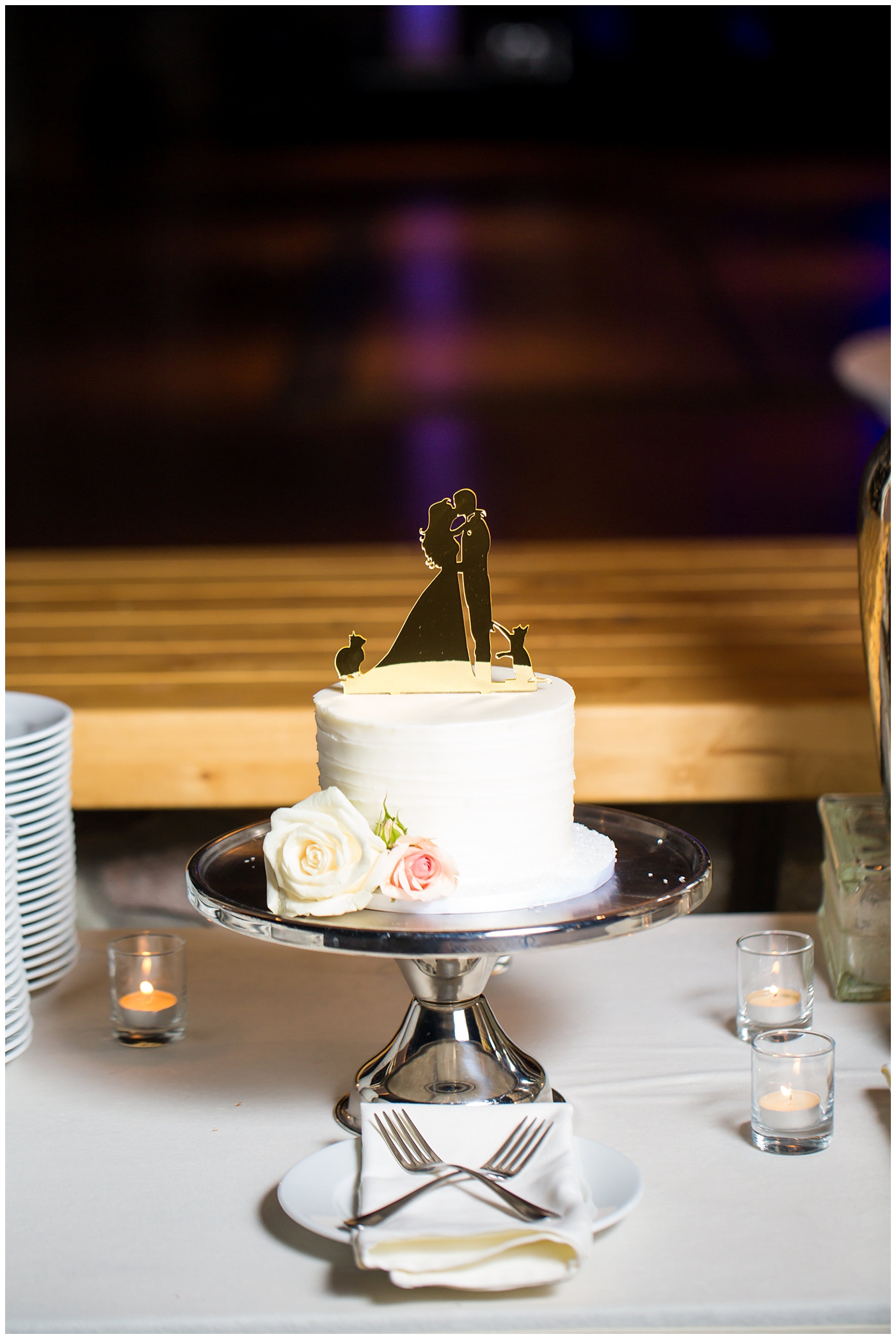 White wedding cake with custom gold cake topper of bride and groom with cats