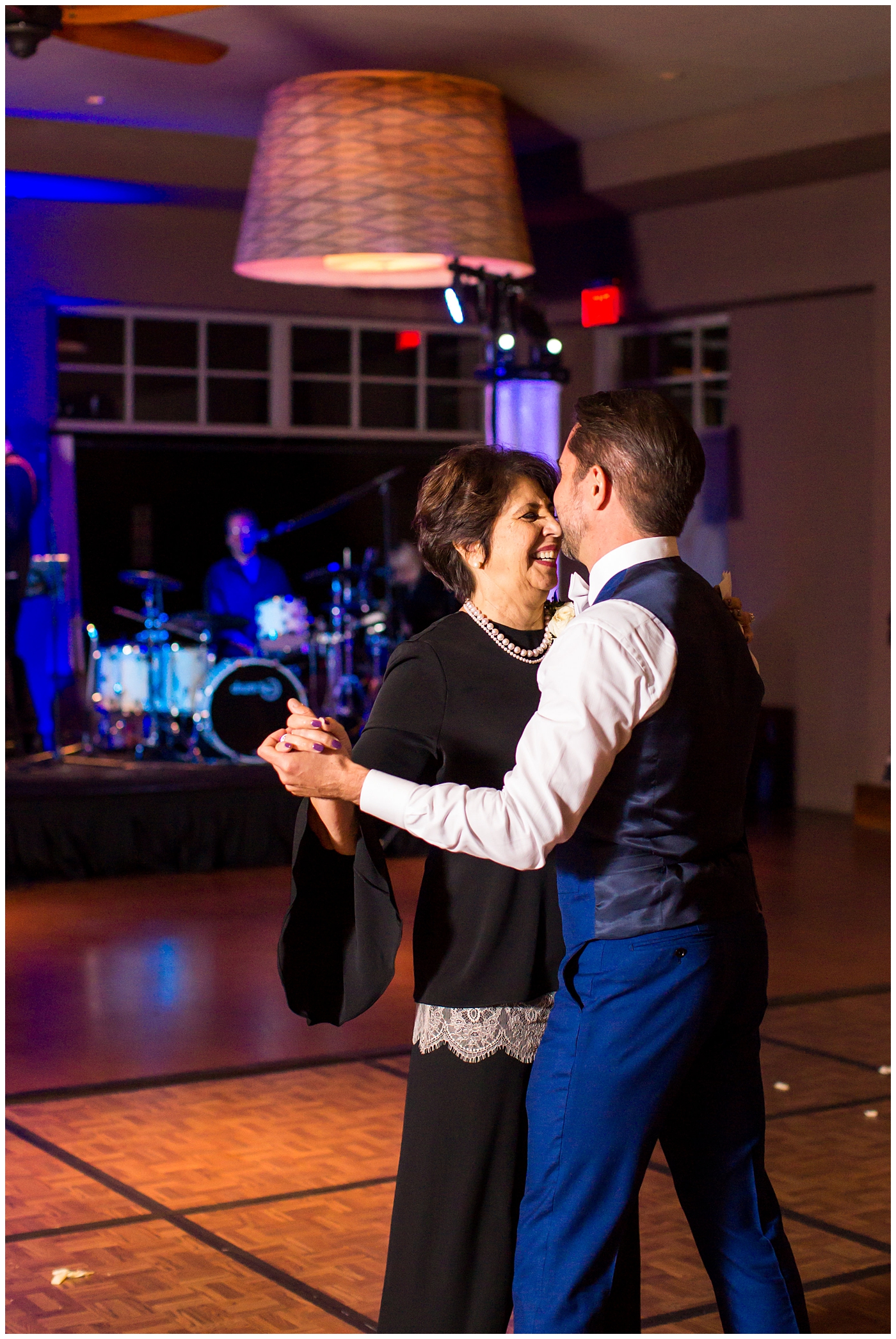 Groom in a custom Brother's Tailors Blue suit dancing with his mother at wedding reception