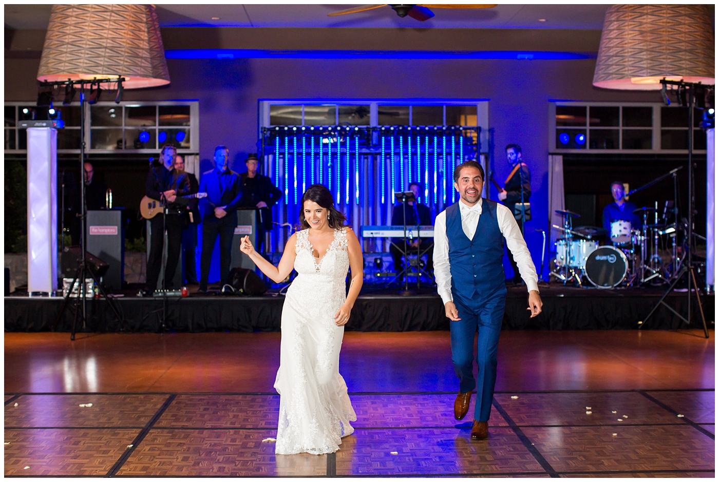 Bride in Justina Alexander dress with groom in custom Brother's Tailors blue suit dancing at their reception