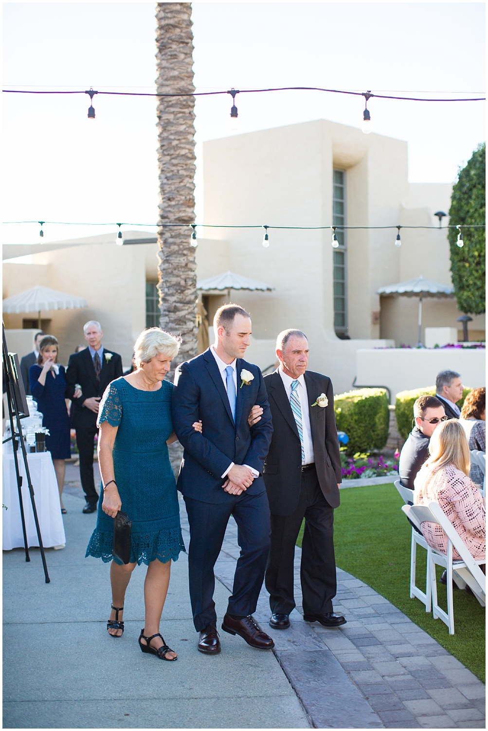 groom walking down aisle with parents at wedding ceremony