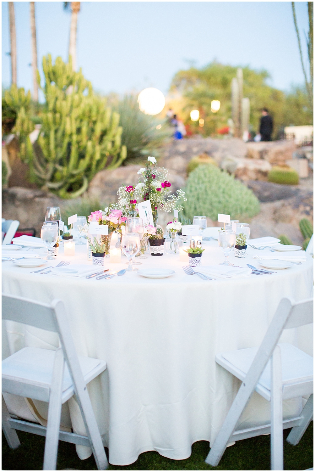 reception table with white linens and chairs with flowers