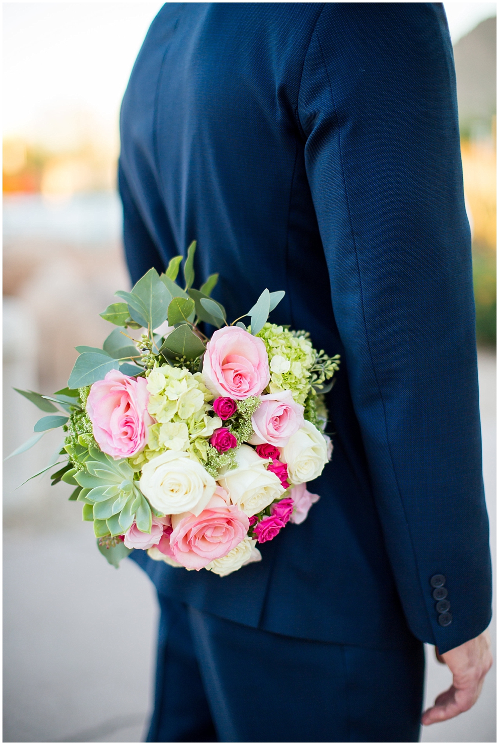 bride in essence design wedding dress holding a pink and white rose bouquet with green and groom in navy blue suit wedding portrait