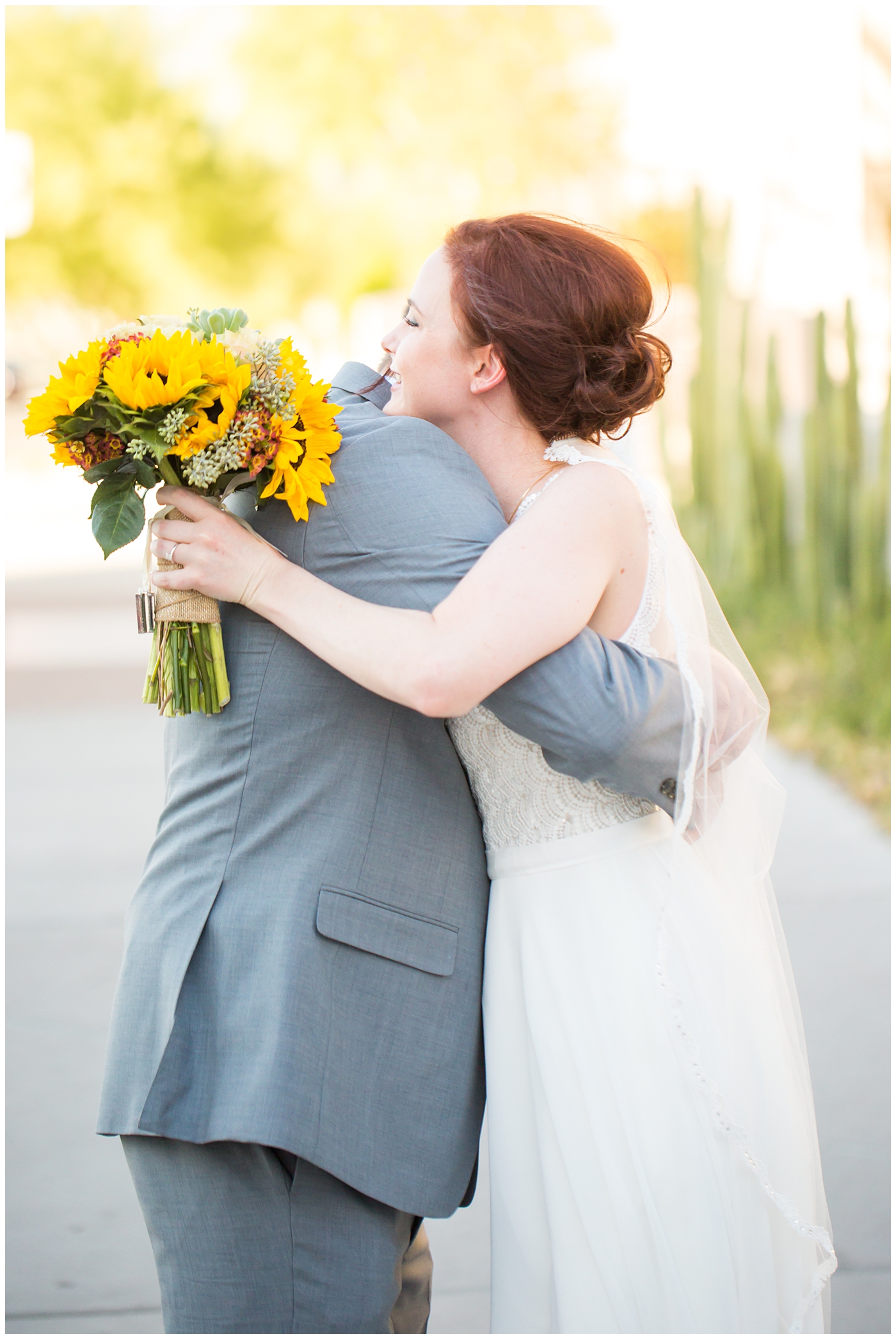bride in white dress with sunflower and succulent bouquet and groom in gray suit wedding portrait