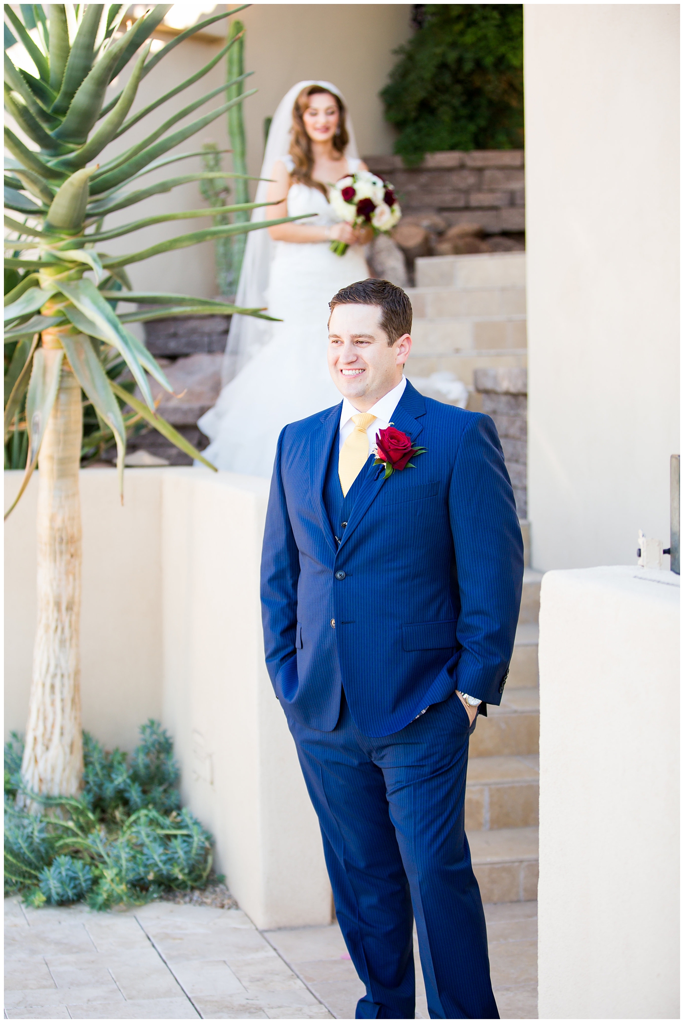 groom in blue suit with yellow tie and red rose boutonniere first look
