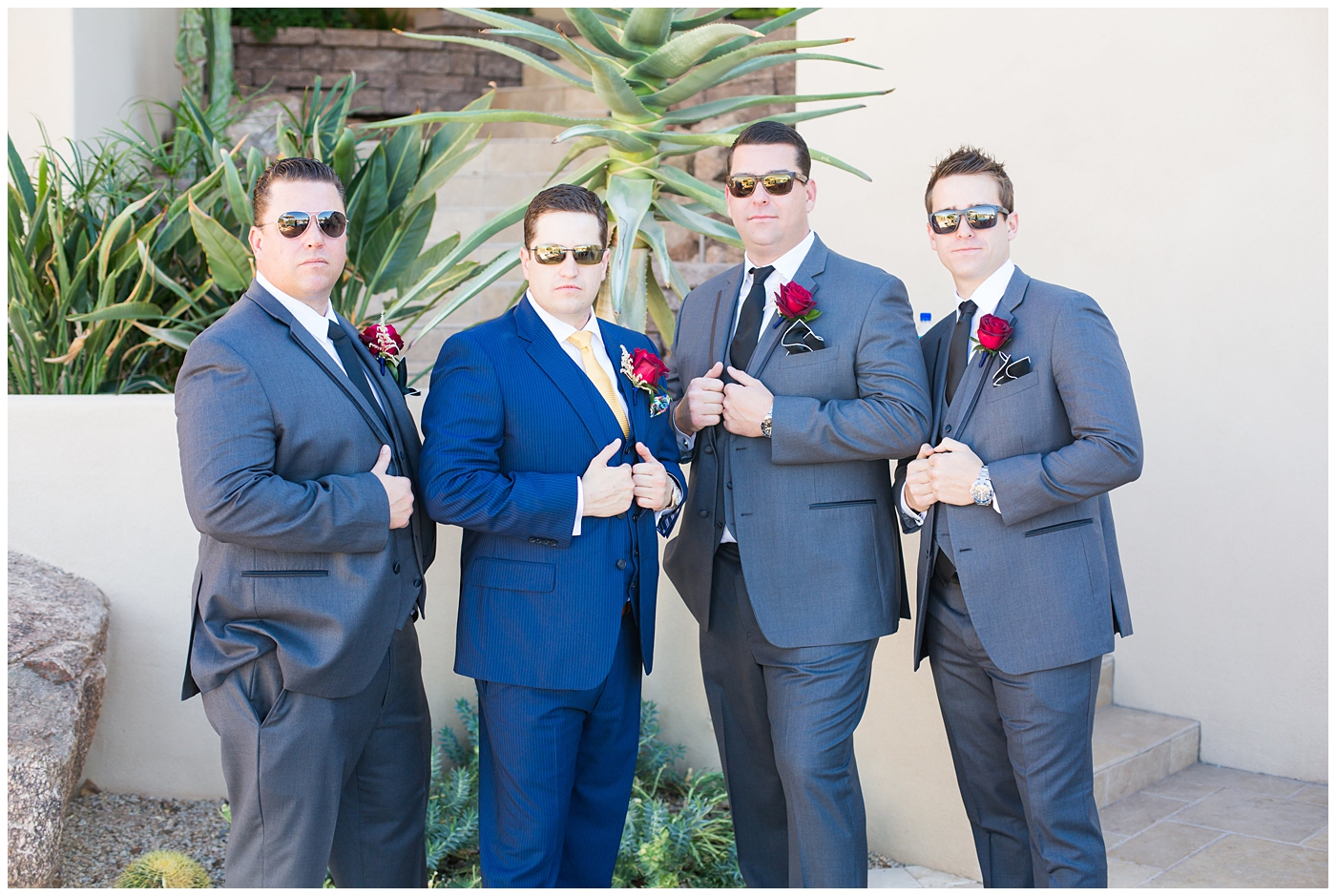 groom in blue suit with yellow tie and red rose boutonniere and groomsmen in gray suits