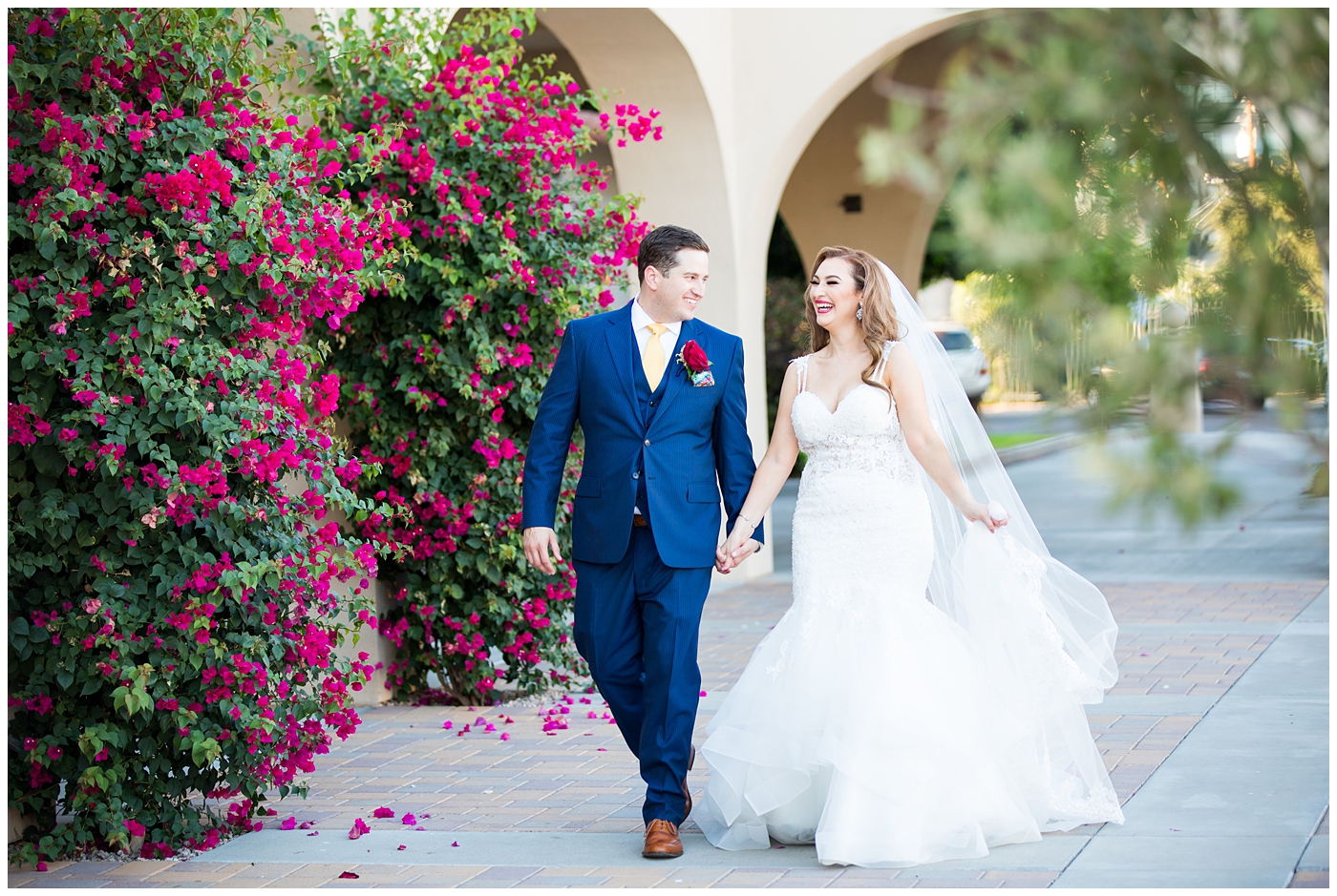 groom in blue suit with yellow tie and red rose boutonniere and bride in morilee wedding dress with red and white rose bouquet portrait