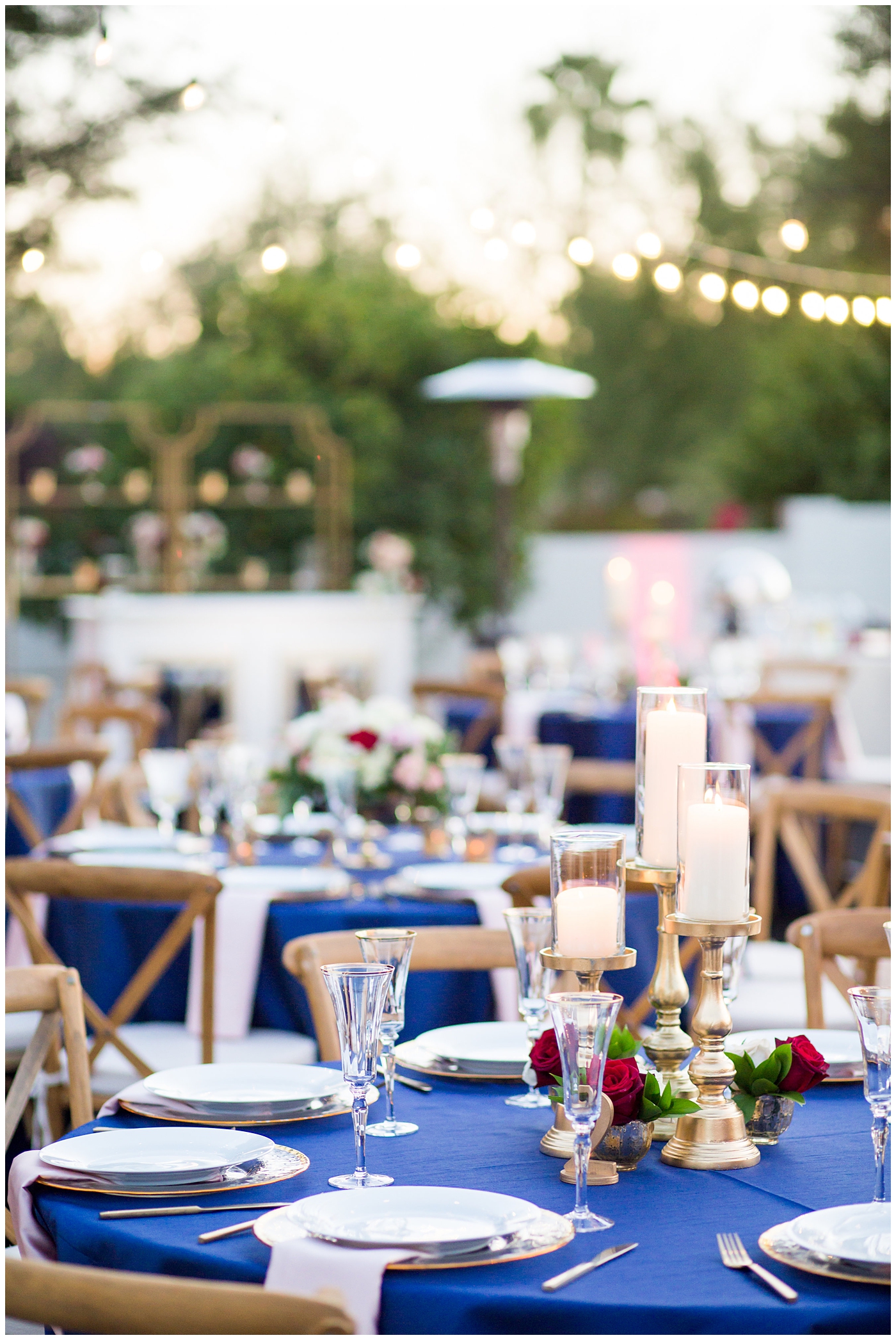 reception details tables with blue linens, gold table numbers and candles with white and red rose centerpieces