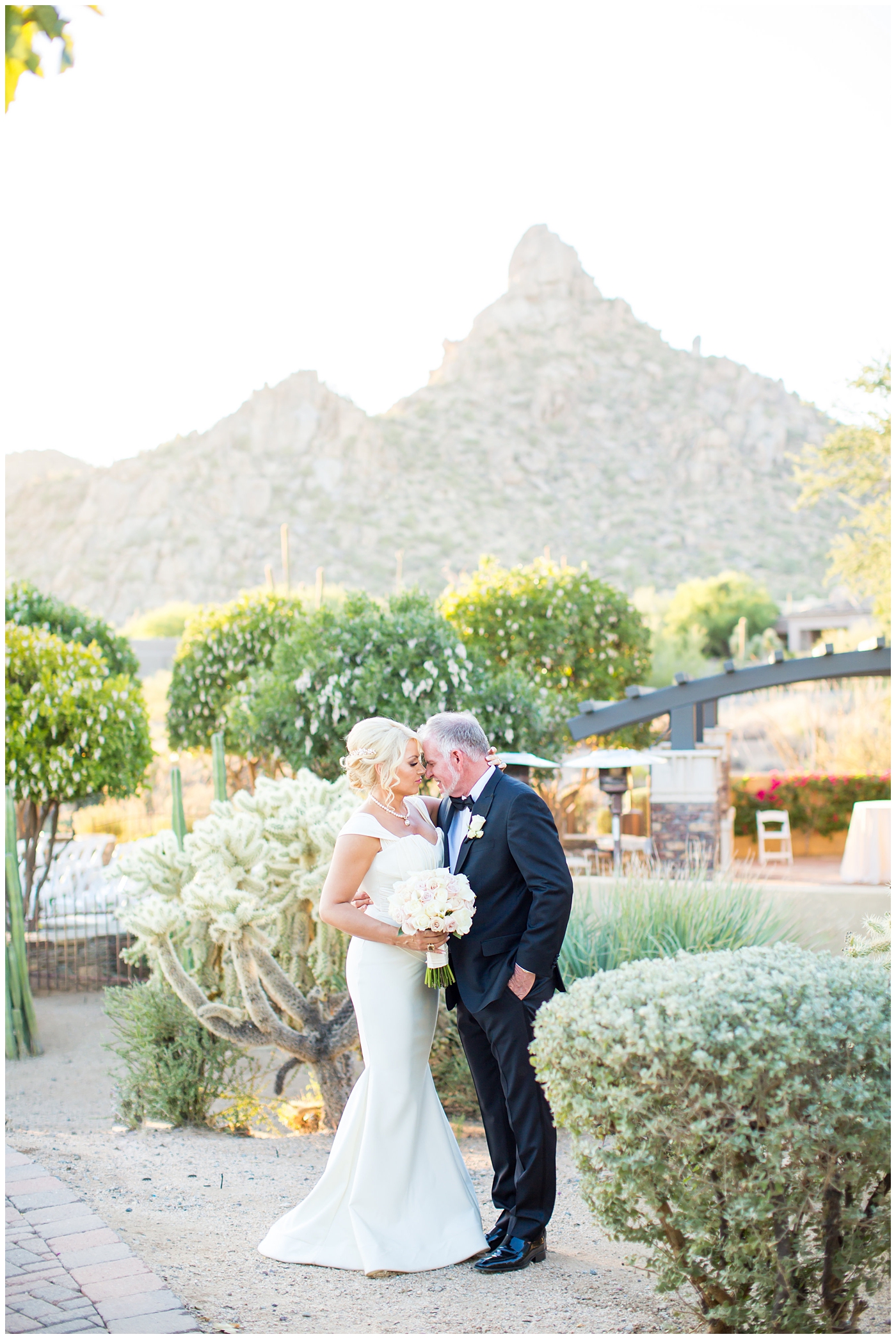 Bride in cap sleeve dress and groom in black tux with mountain in background