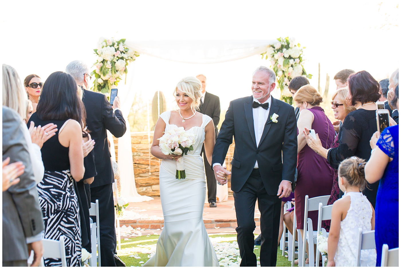bride in cap sleeve dress with groom in tux walking down aisle