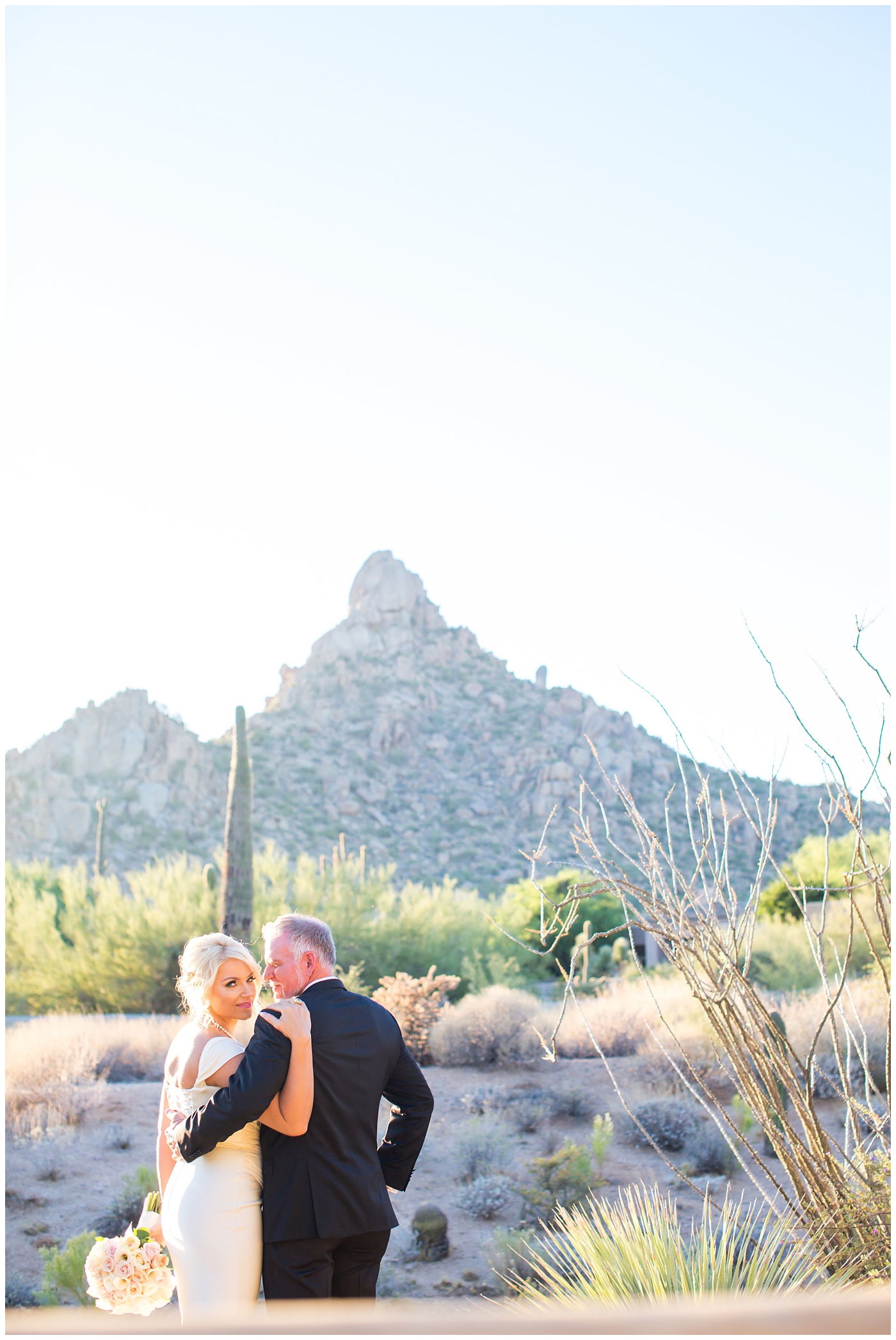 Bride in cap sleeve dress and groom in black tux with mountain in background