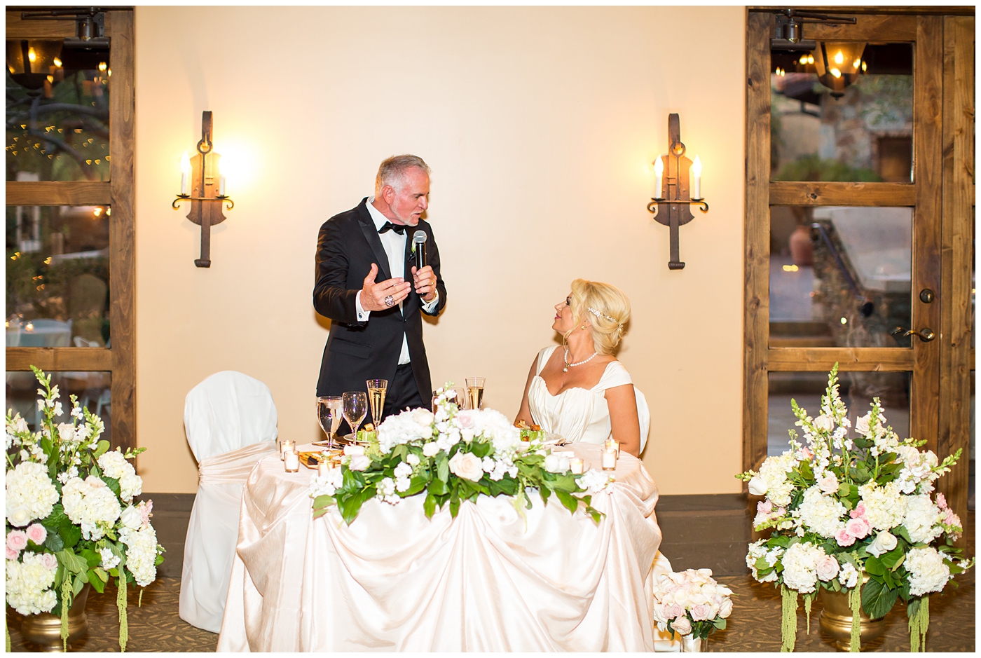Bride in cap sleeve dress and groom in black tux toast