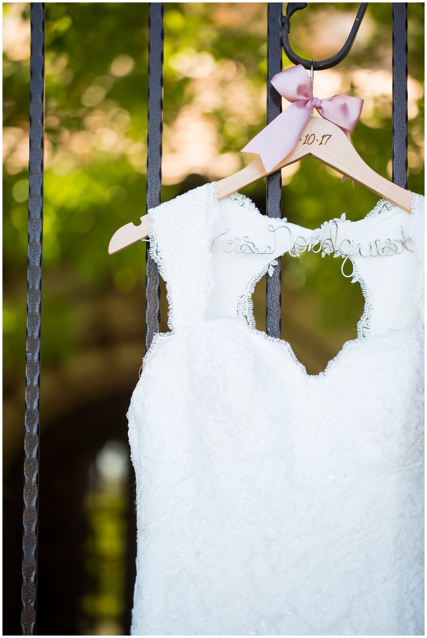 Essense Designs wedding dress with cap sleeves hanging up in arch on custom name hanger