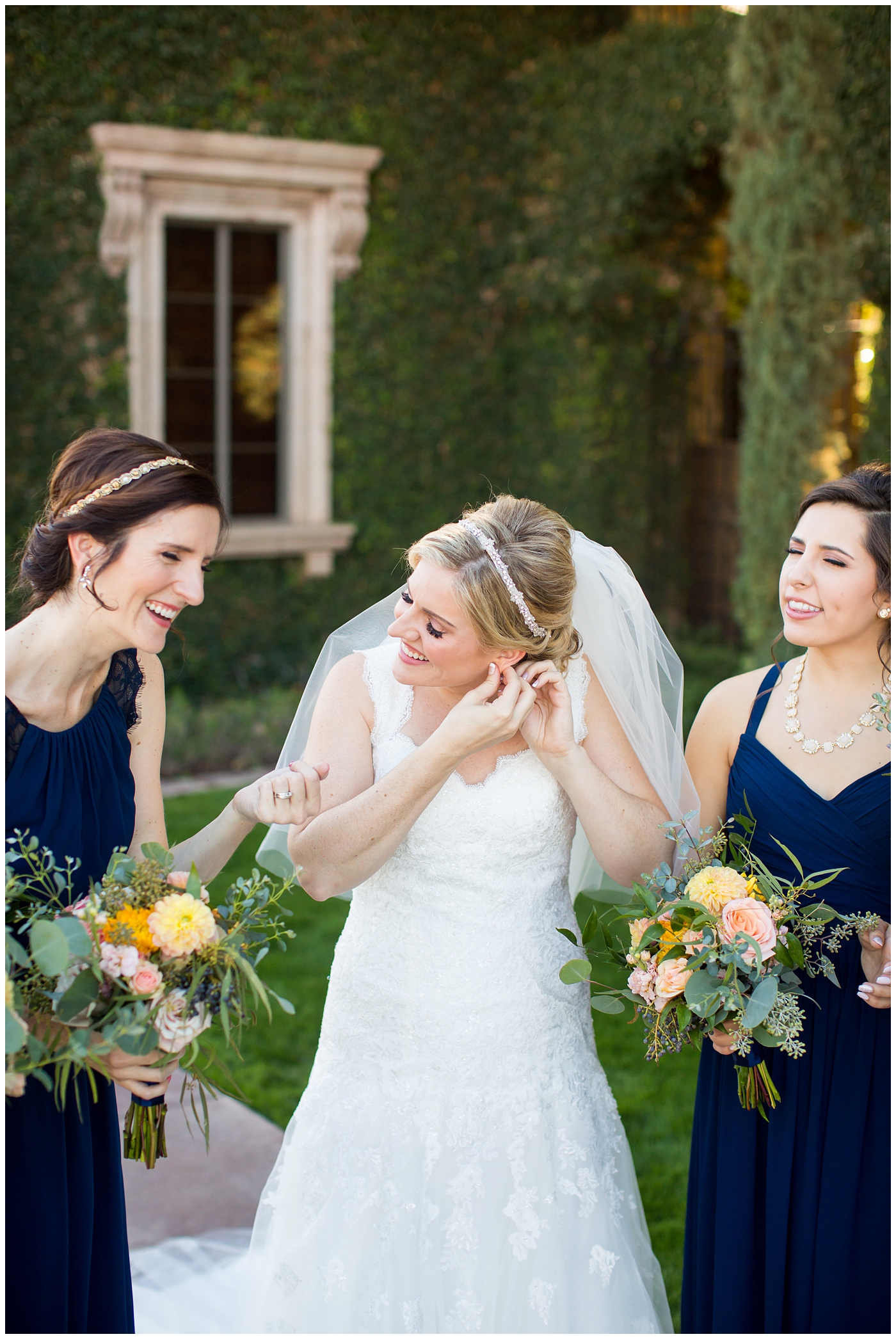 bride in essence designs wedding dress with cap sleeves getting ready with bridesmaids in navy helping