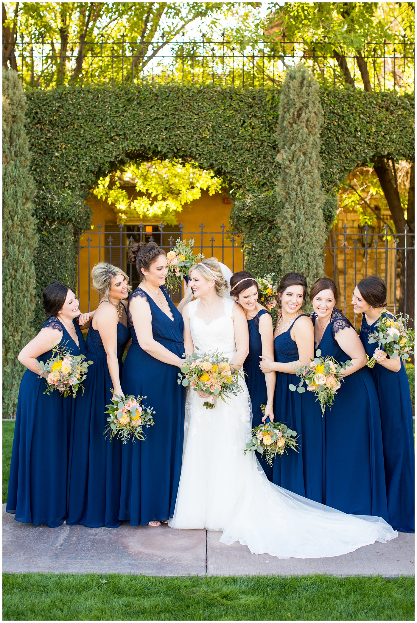 bride in essence designs wedding dress with cap sleeves portrait group shot with bridesmaids in navy blue long dresses