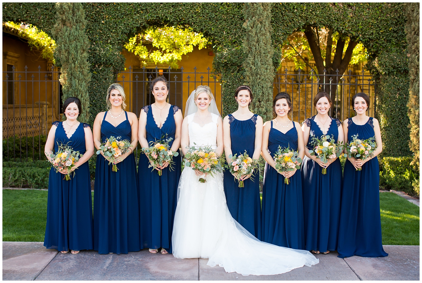 bride in essence designs wedding dress with cap sleeves portrait group shot with bridesmaids in navy blue long dresses
