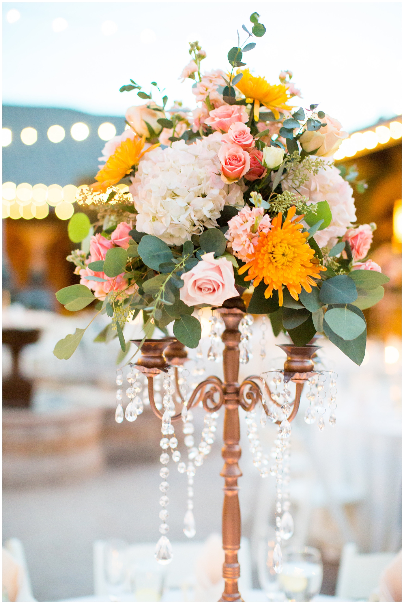 tall candelabra with orange roses, greenery, yellow flowers and jewels hanging wedding reception details