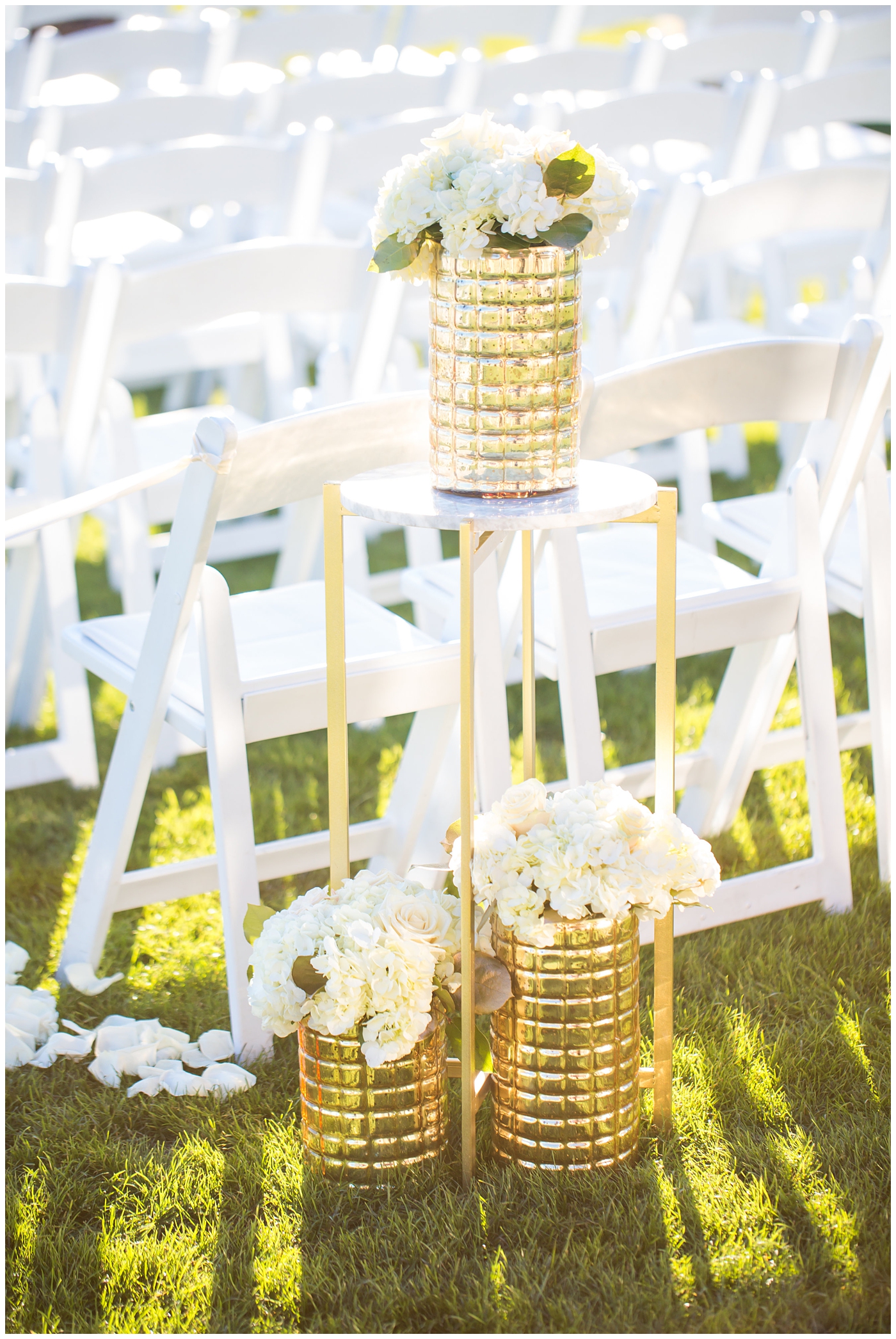 gold vases with white roses in walkway of wedding ceremony aisle
