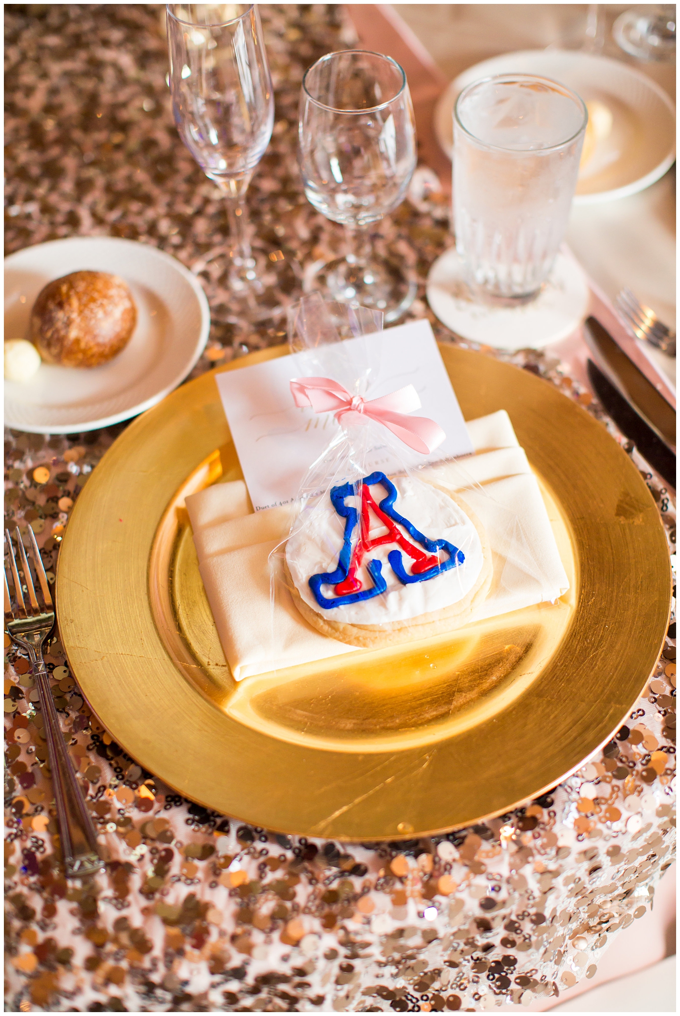 gold charger with ivory napkin and UofA cookie on blush rose gold sequin linen for wedding reception =