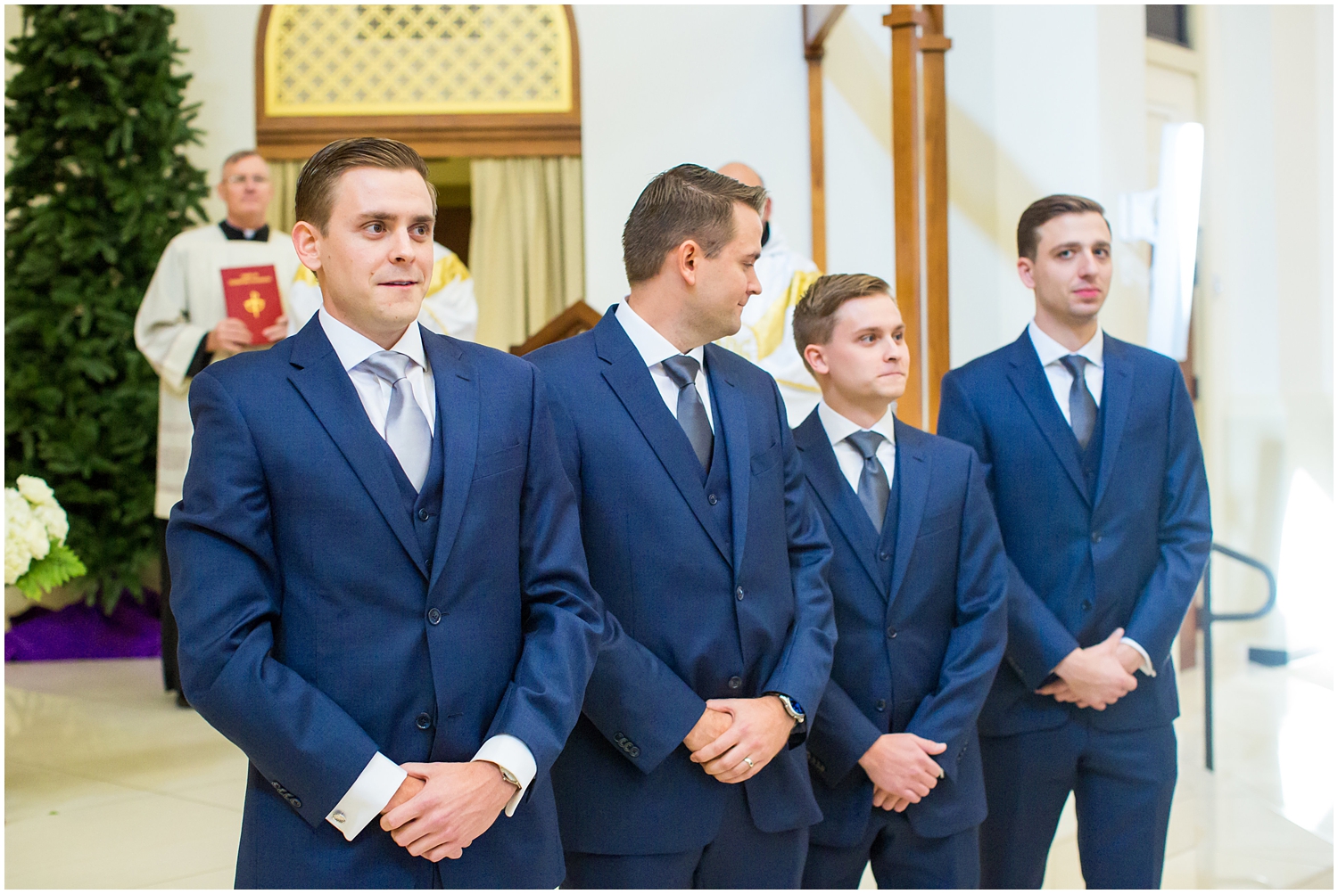 groom in navy blue suit with light blue tie waiting for bride to come down the aisle on wedding day