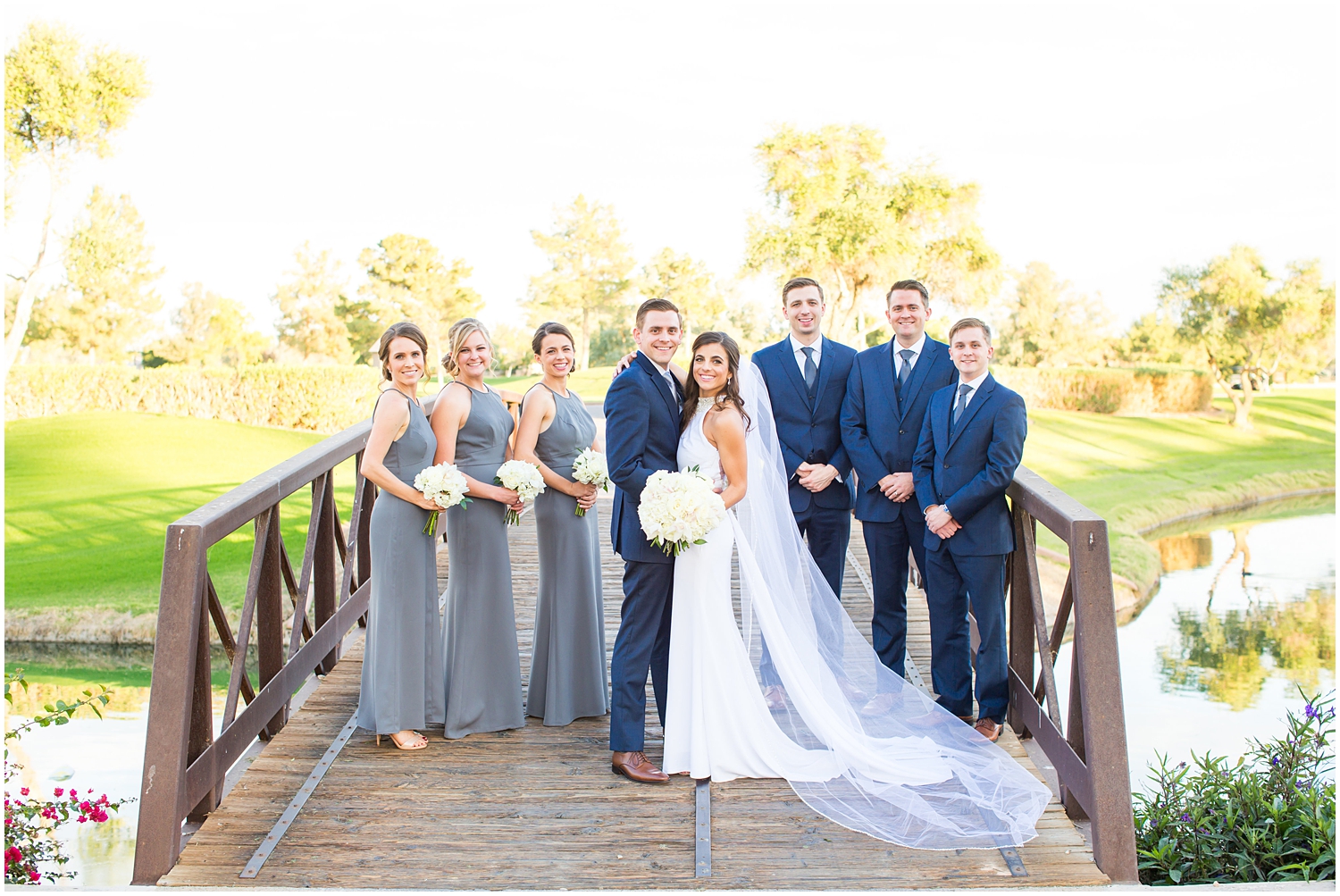 bride in demetrios bridal gown racerback with sheer beading with white hydrangeas bouquet with bridesmaids in gray dresses and groom and groomsmen in navy blue suit with light blue tie wedding party picture