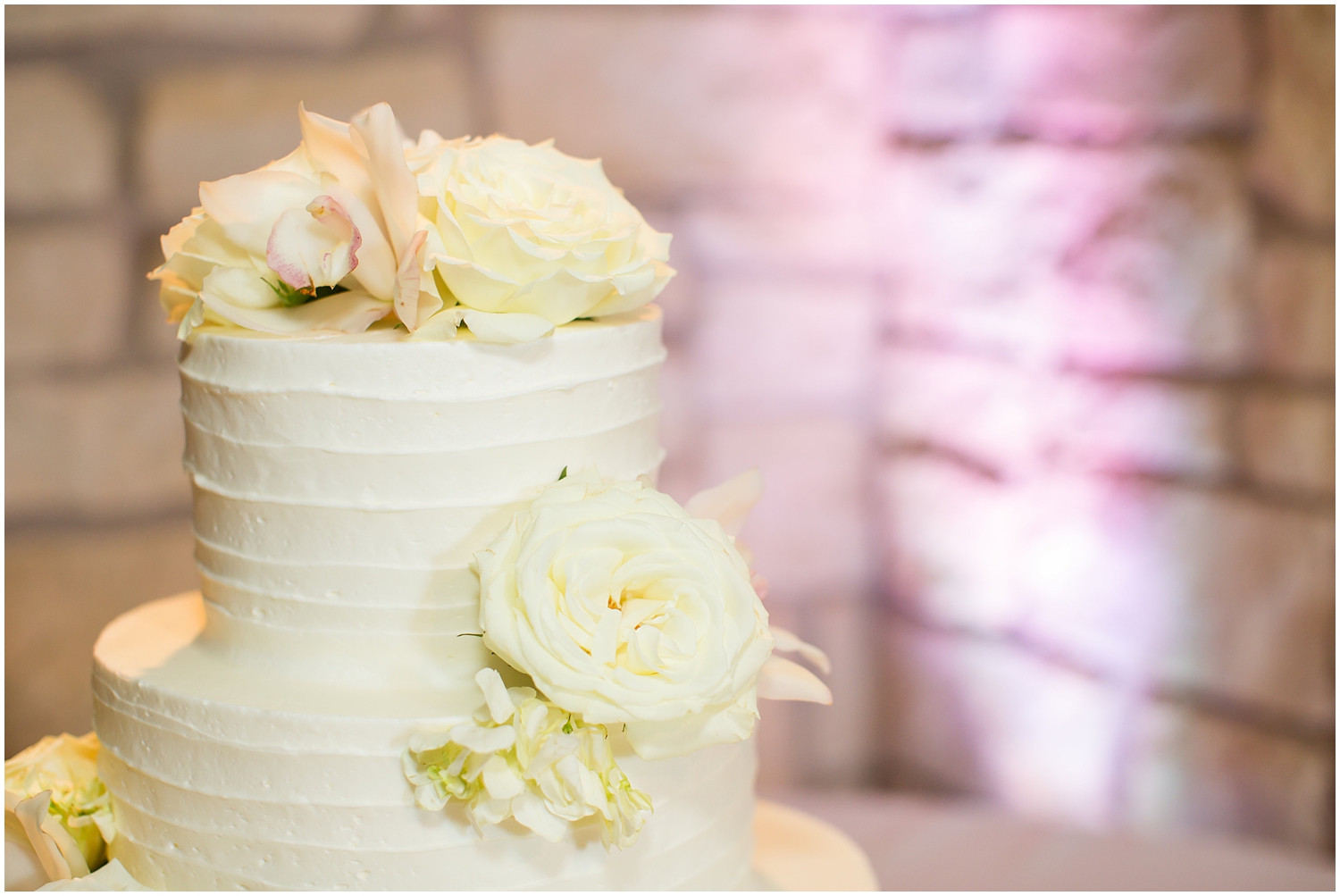 four tier white wedding cake with frosting texture and white roses and hydrangeas for wedding day reception