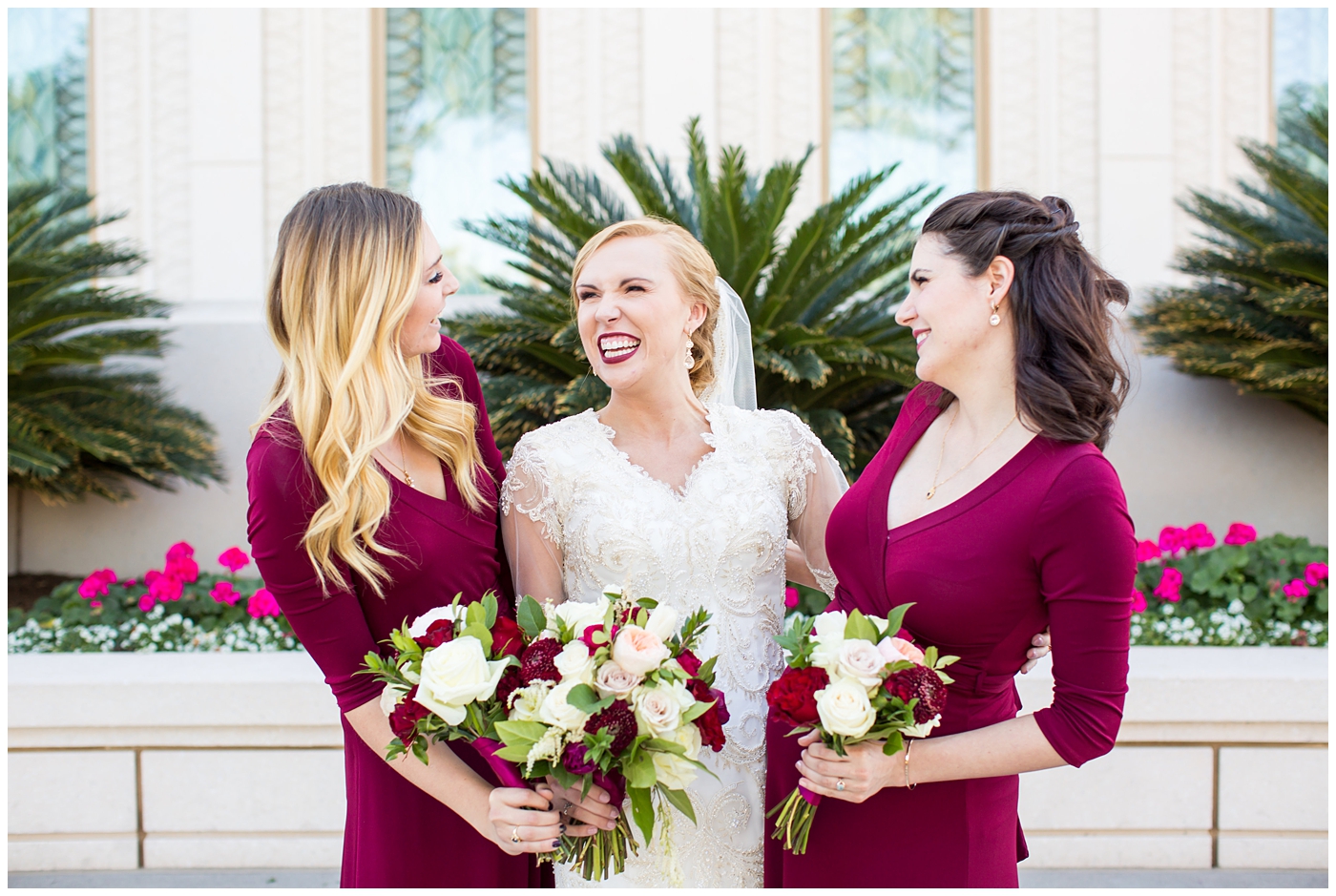 bride in sleeved lace dress with burgundy, white, and green wedding bouquet with bridesmaids in long sleeve burgundy dresses wedding day portrait at Gilbert LDS temple