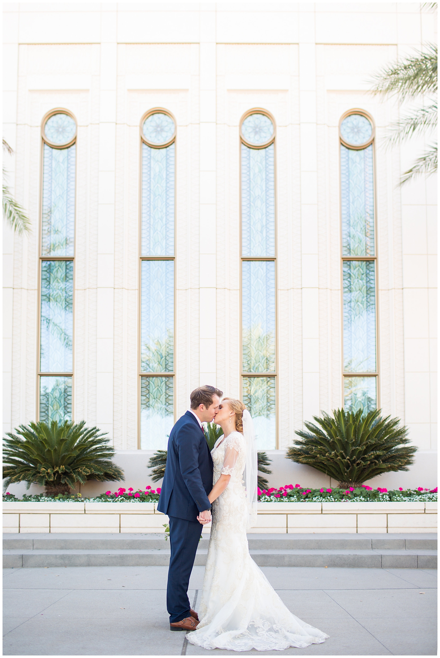 bride in sleeved lace dress with burgundy, white, and green wedding bouquet and groom in navy suit with burgundy tie wedding day portrait at Gilbert LDS temple