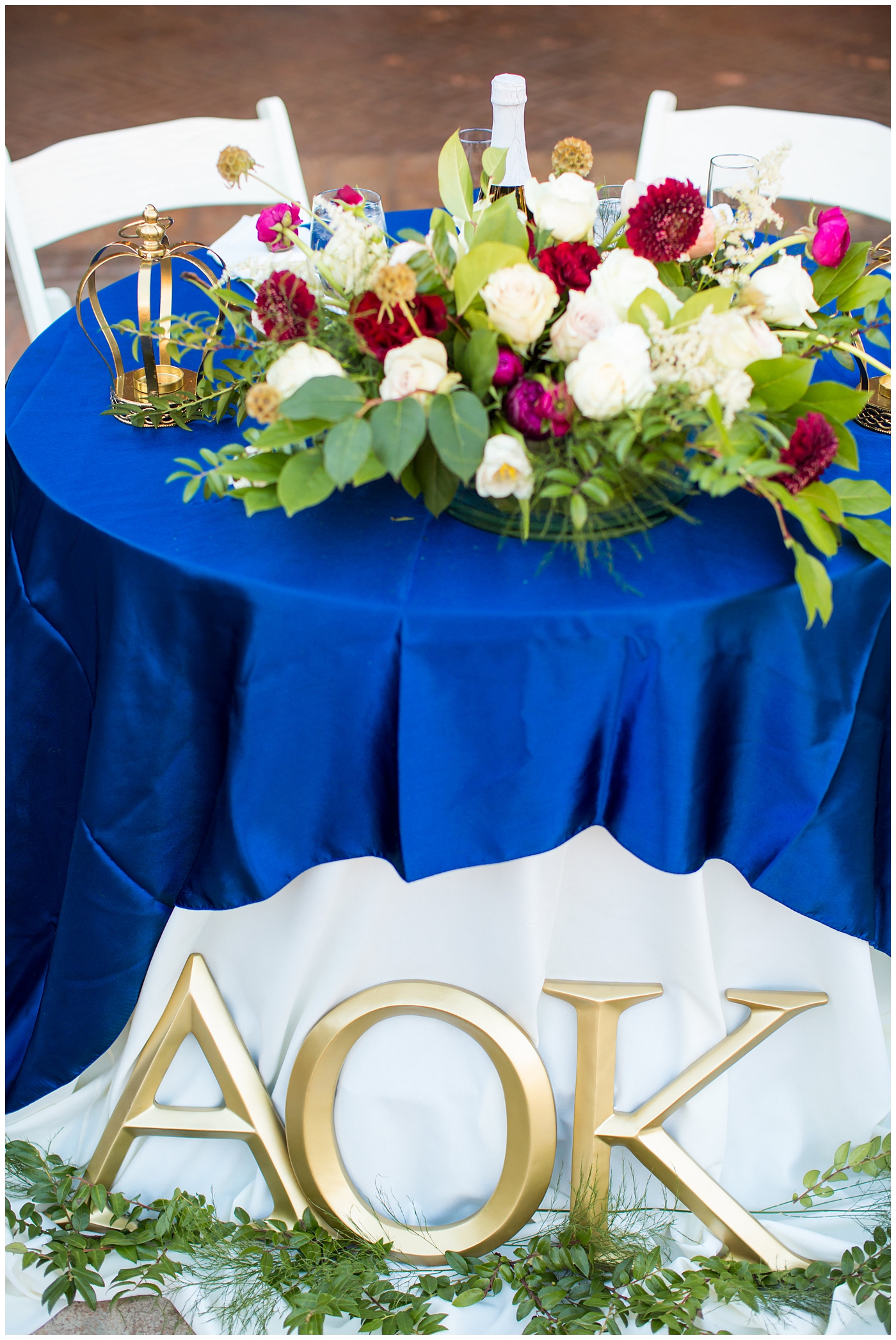 blue table cloth with white plate and burgundy floral arrangements wedding reception details at Villa Siena