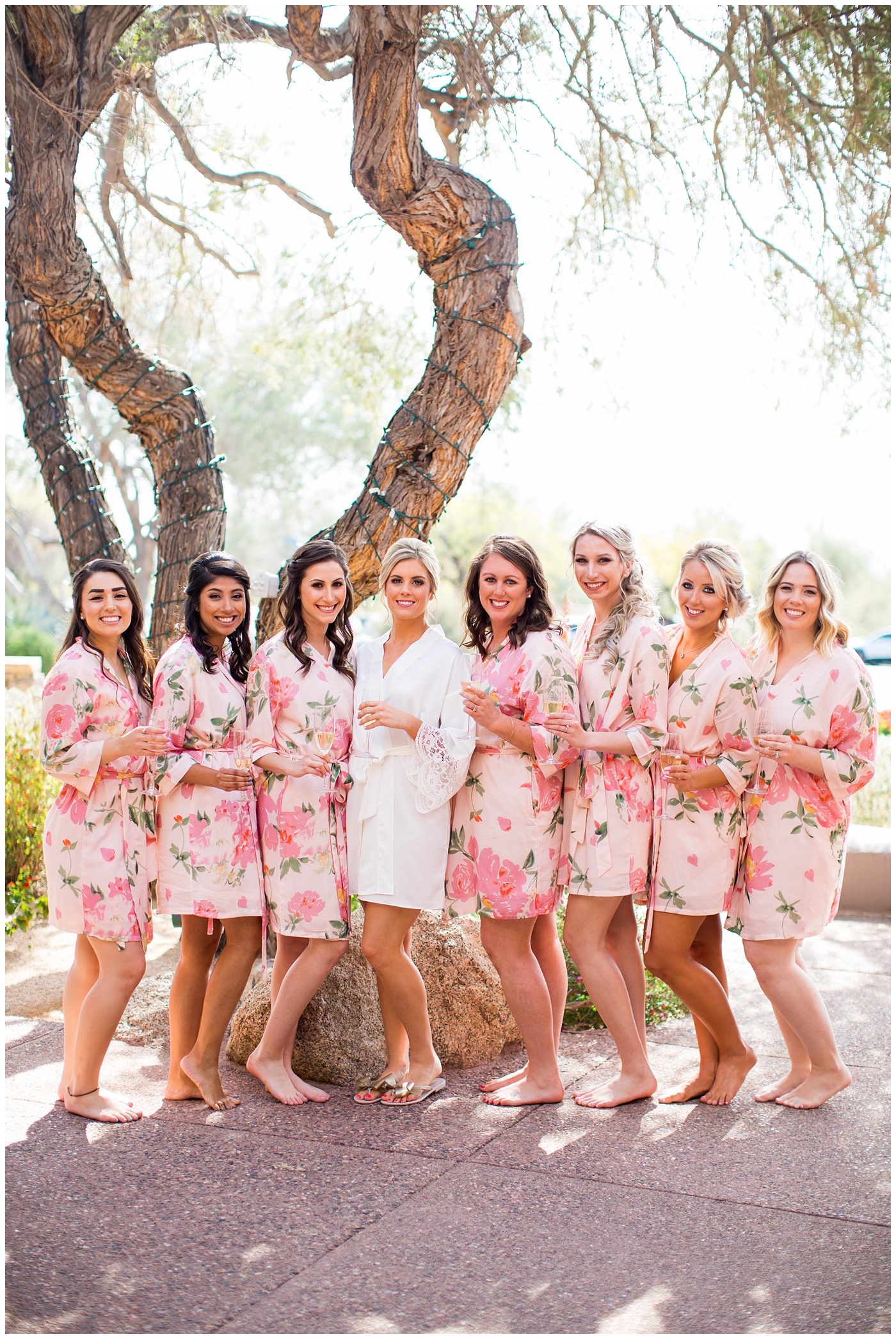 bride with bridesmaids in silk pink flower robes getting ready on wedding day