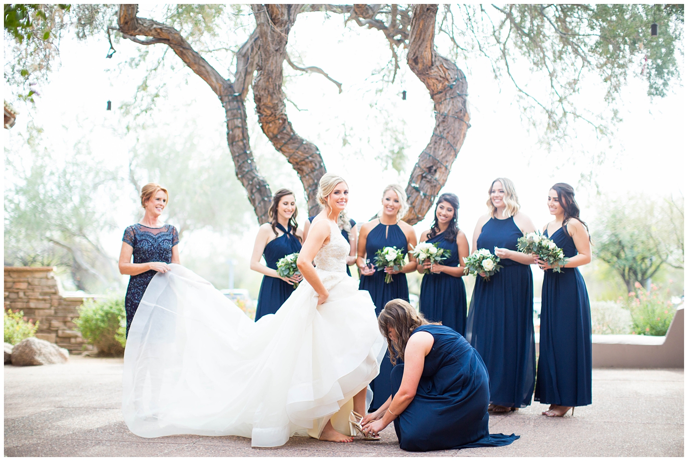 bride in backless lace wedding dress with bridesmaids in navy blue dress getting ready on wedding day