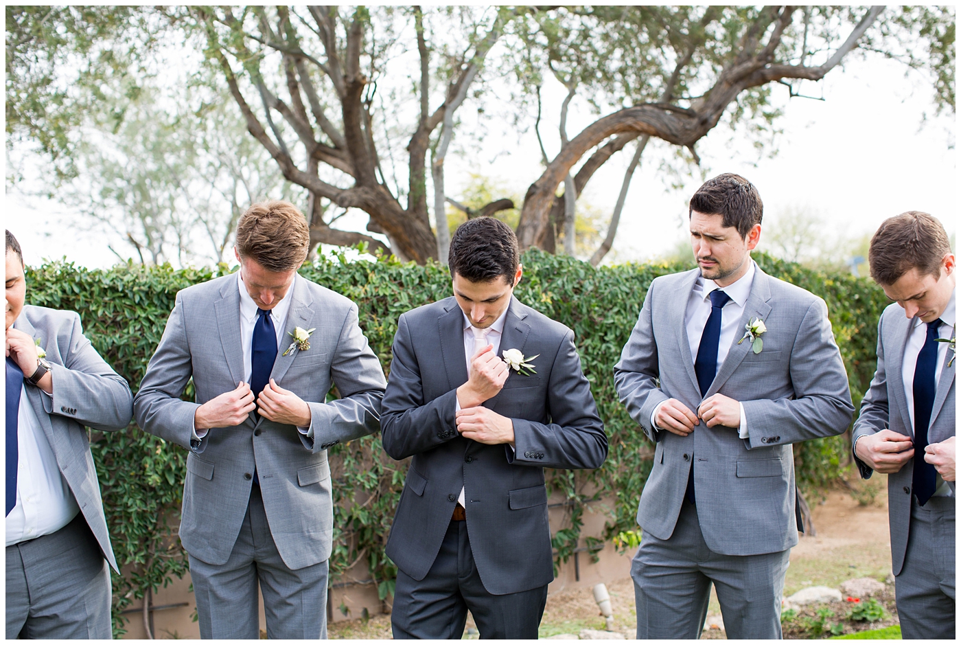 groom in gray suit with pink tie with groomsmen with navy ties on wedding day