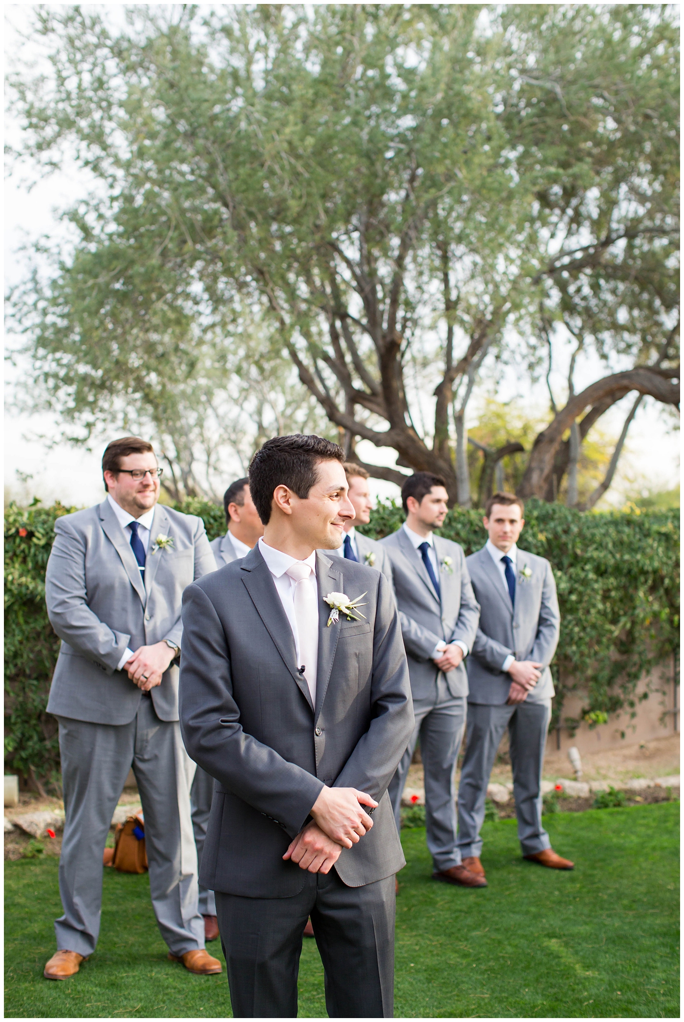 groom in dark gray suit with pink tie on wedding day waiting for bride to walk down aisle