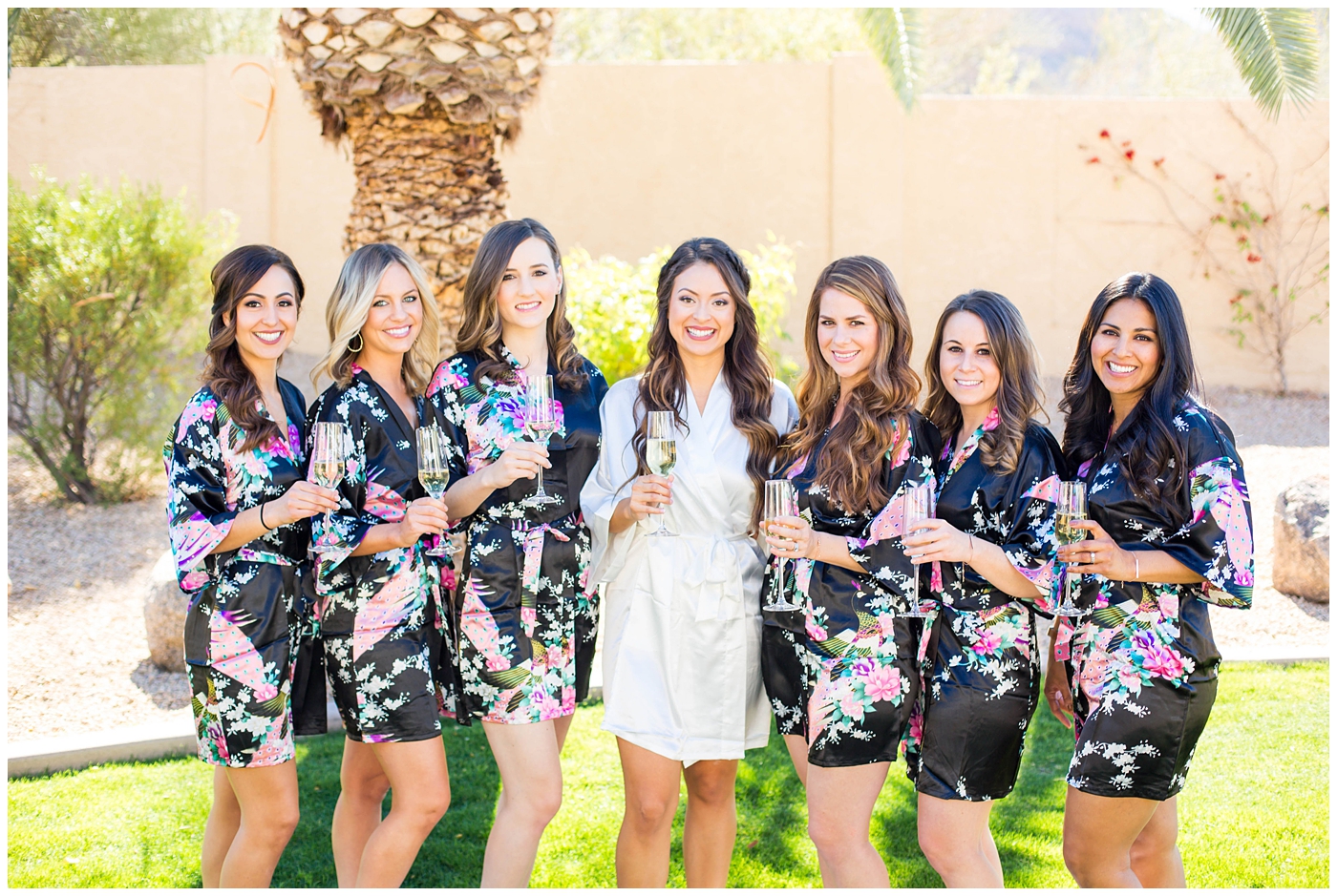 bride with bridesmaids in matching floral black silk robes on wedding day