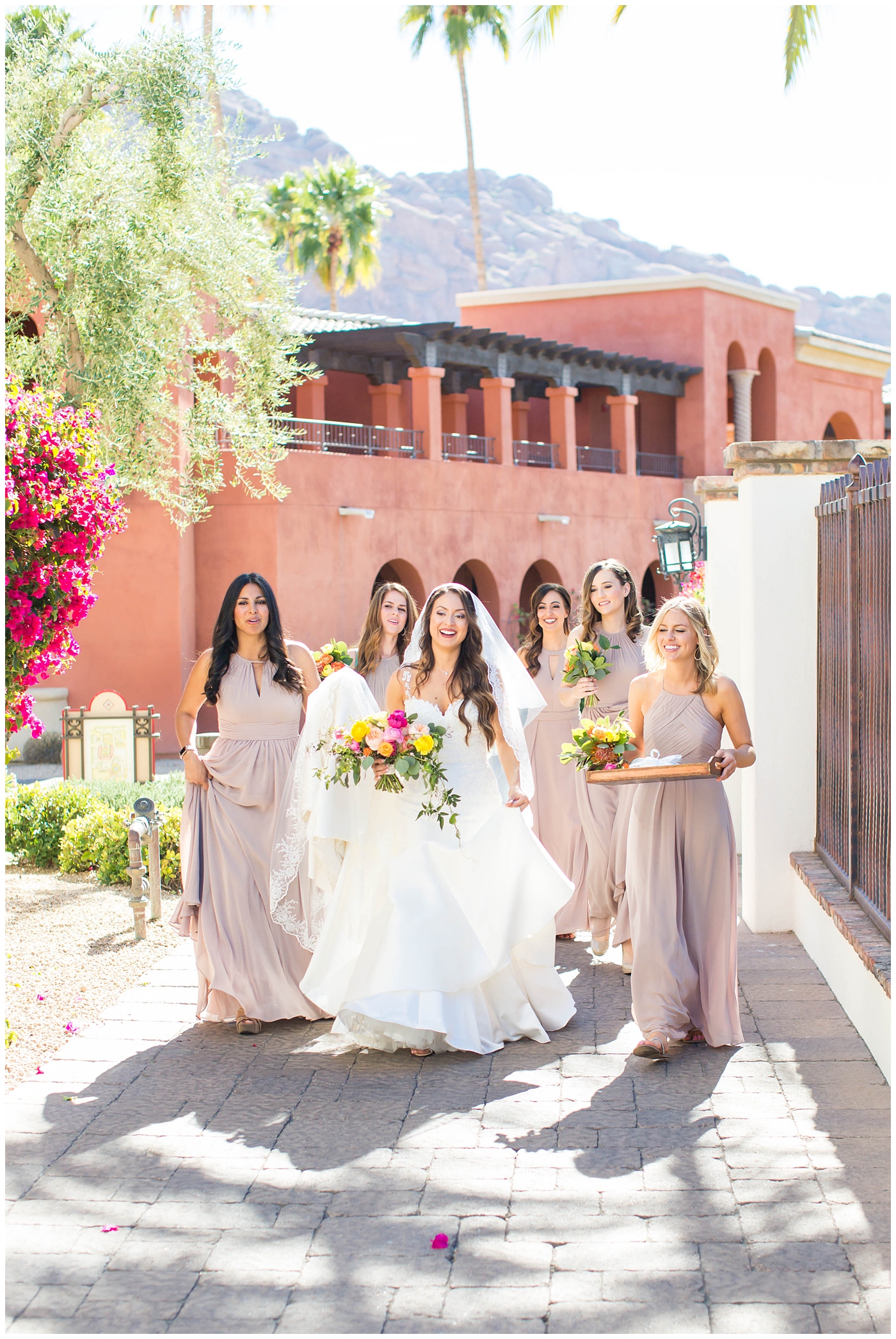 bride in lace cap sleeve wedding dress walking with bridesmaids in azazie dresses on wedding day