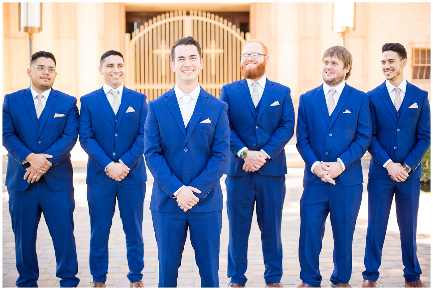 groom in blue suit with blush tie on wedding day with groomsmen in blue suits