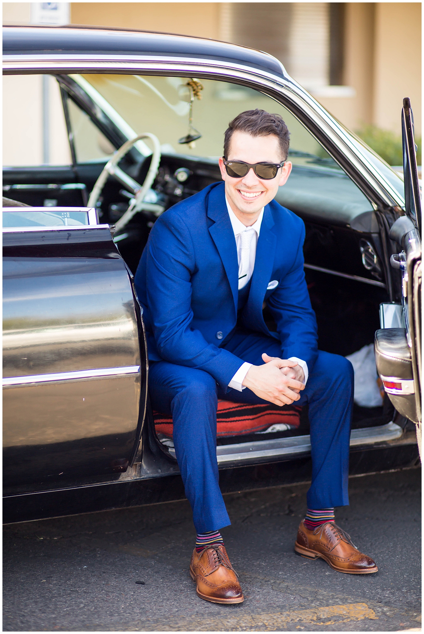 groom in blue suit in old car portrait on wedding day