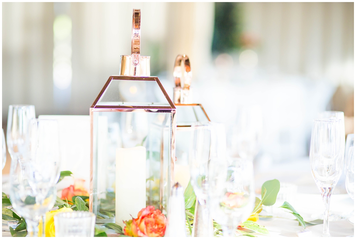 wedding reception details with white tables and chairs with gold stands with white, bright pink, orange, yellow and green flowers and copper lanterns