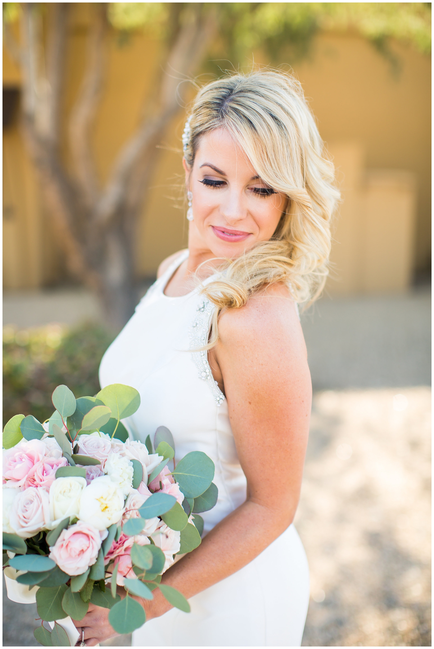 gorgeous bride with side swept hair in racerback pronovias wedding dress and blush pink, white rose and eucalyptus greenery wedding bouquet bridal portrait