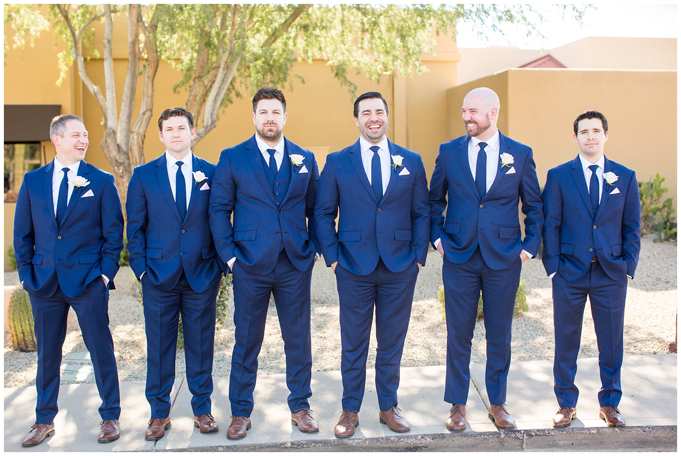 groom in navy suit and tie with pink rose boutonniere bridal party groomsmen in navy blue suits on wedding day