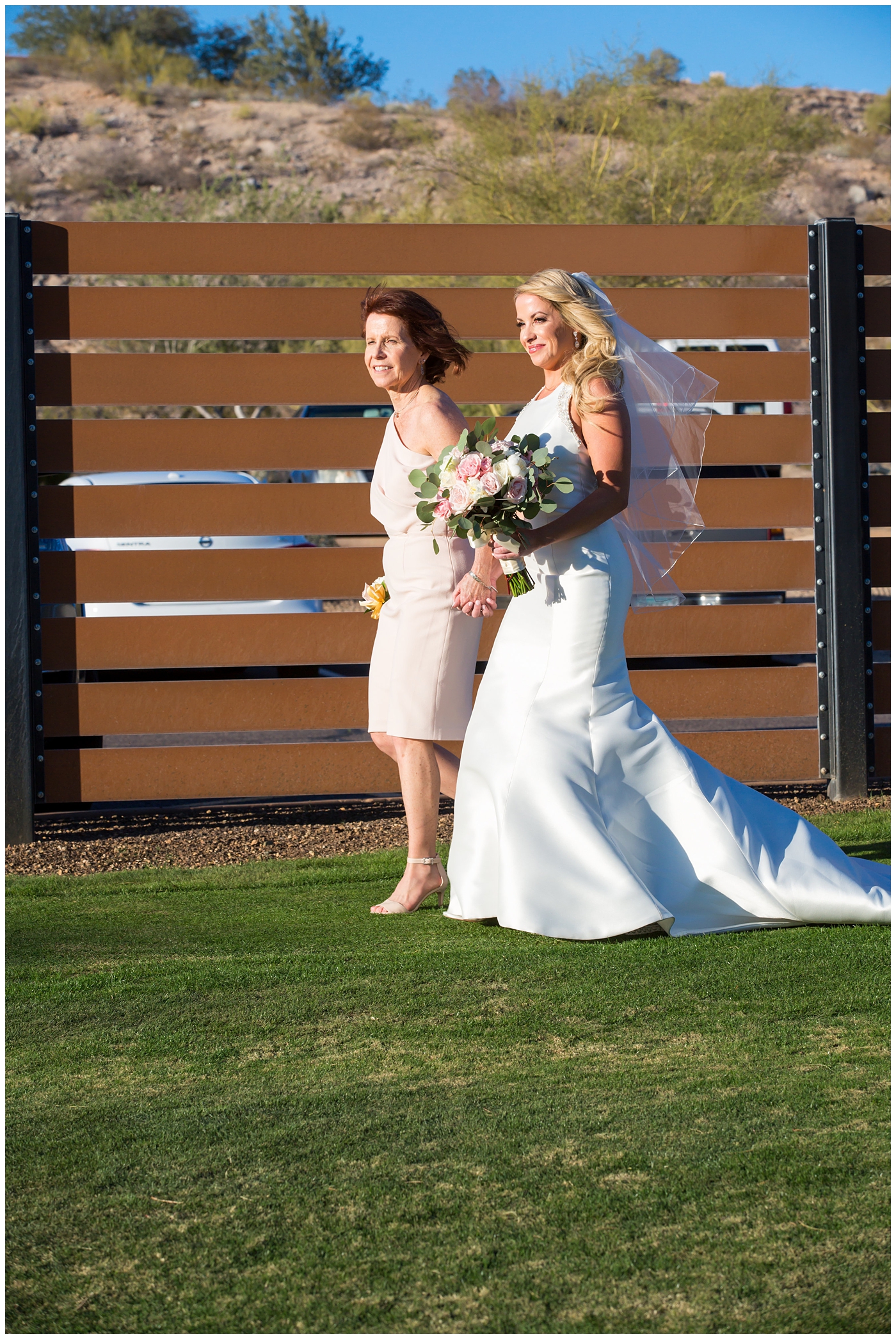 gorgeous bride with side swept hair in racerback pronovias wedding dress and blush pink, white rose and eucalyptus greenery wedding bouquet walking down the aisle at wedding ceremony