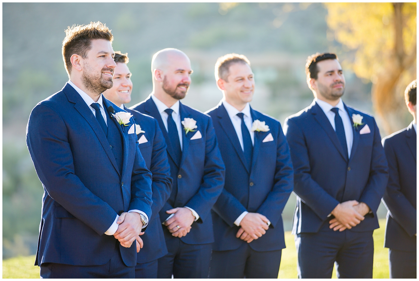 groom in navy suit and tie with blush pink boutonniere seeing his bride at wedding ceremony