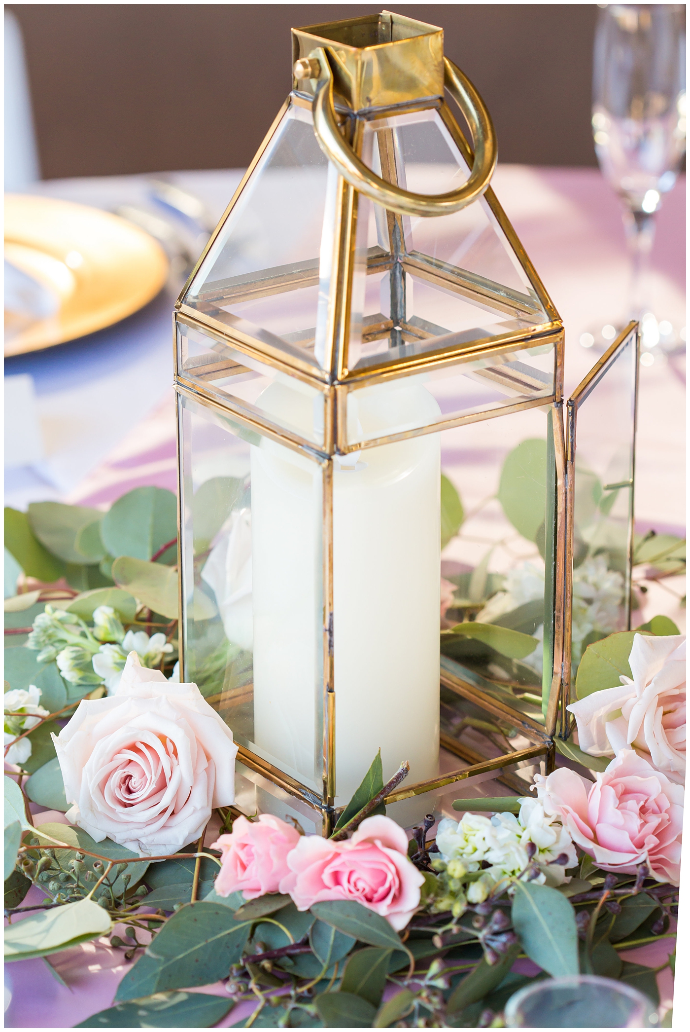 gold glass lantern with candle and pink roses and eucalyptus wedding reception table centerpiece