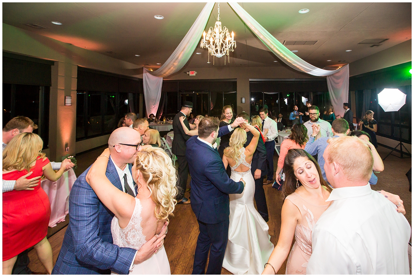 gorgeous bride with side swept hair in racerback pronovias dress and blush pink, white rose and eucalyptus greenery wedding bouquet with groom in navy suit and tie dancing at wedding reception in ballroom